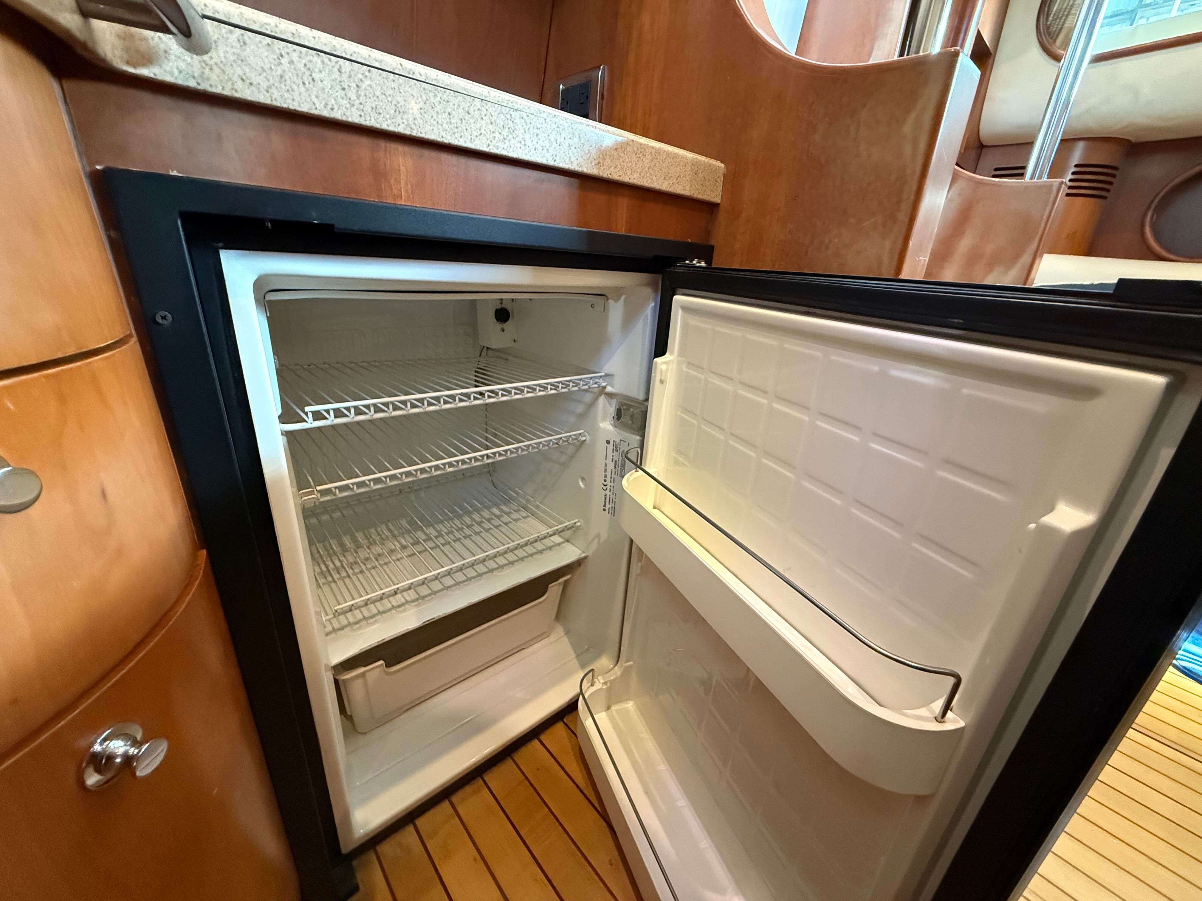 Open fridge in a boat cabin with wooden flooring and countertop.