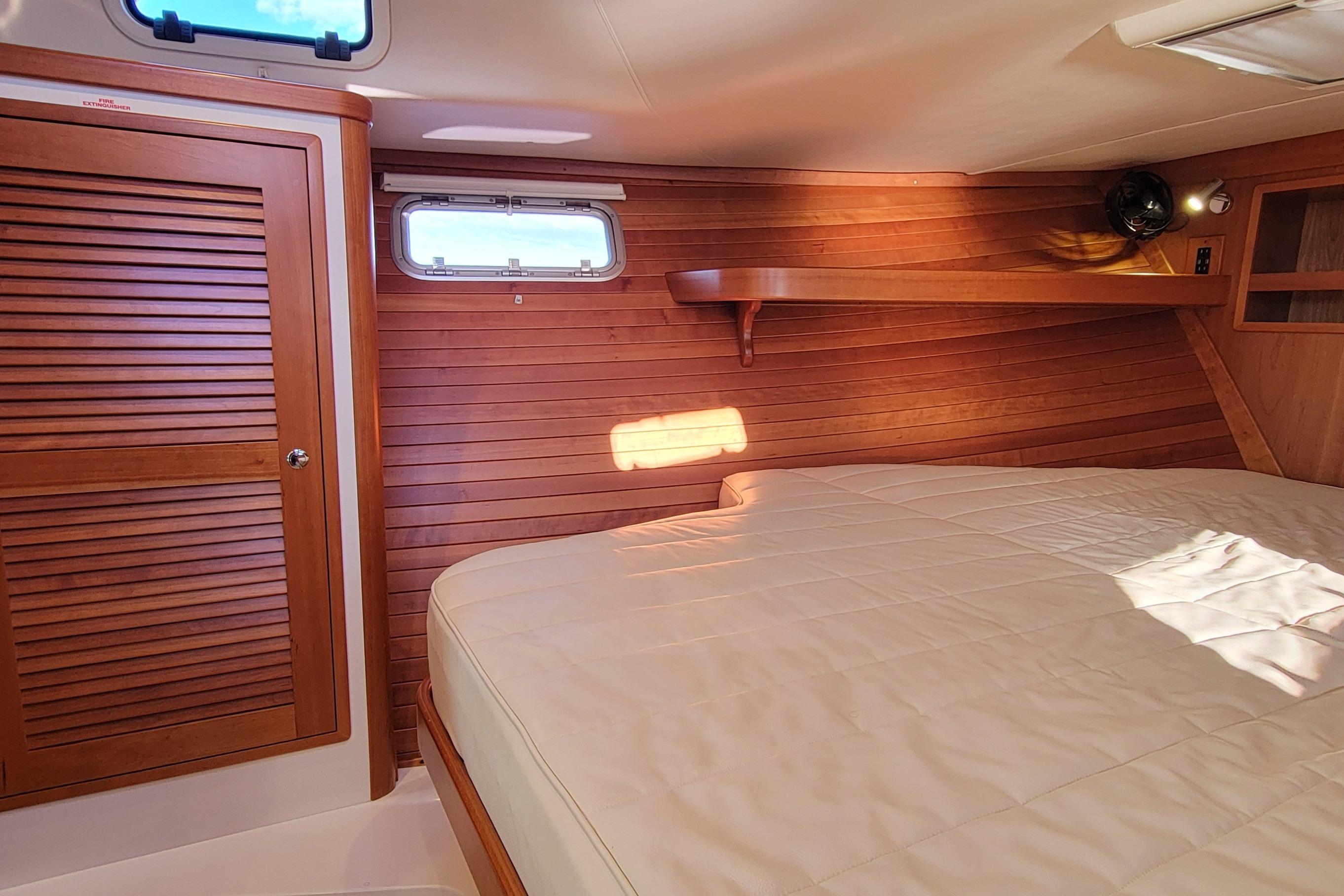 2017 MJM 40z Downeast cabin interior with wooden paneling and cozy bed.