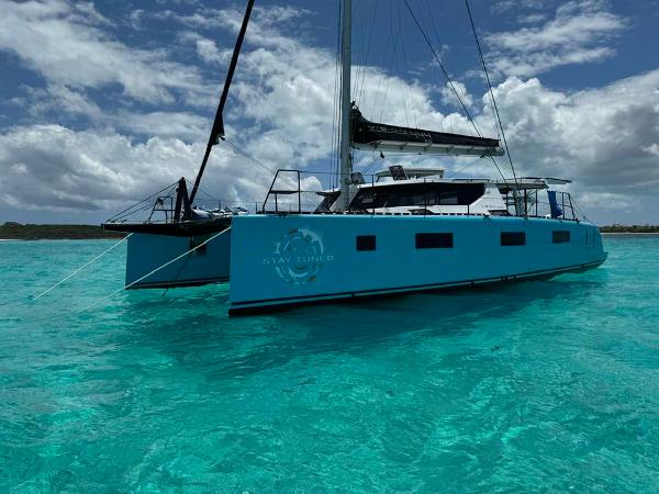 Vision 444 ES 2025 catamaran sailing on clear turquoise waters under a cloudy sky.
