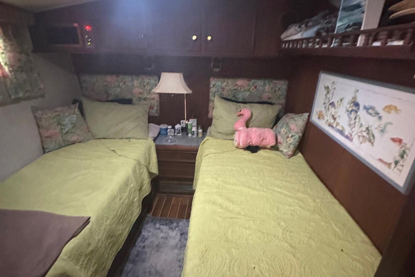 Cozy cabin interior of 1981 Hatteras 43 Convertible with twin beds and decorative pillows.