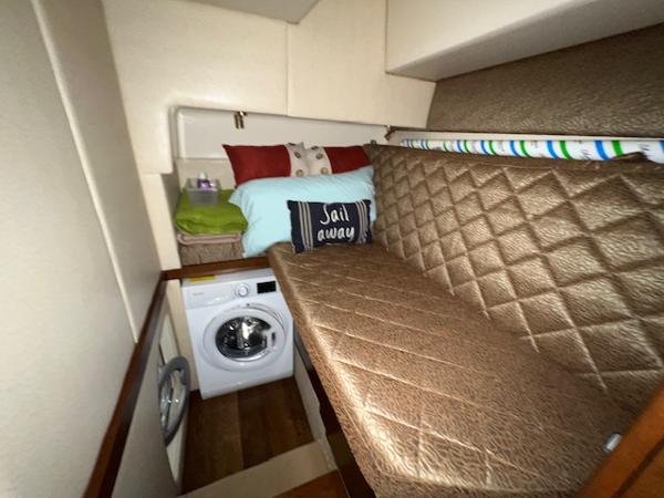 Cozy cabin interior of 2009 Ovation 52 with bed, washing machine, and Sail Away pillow.