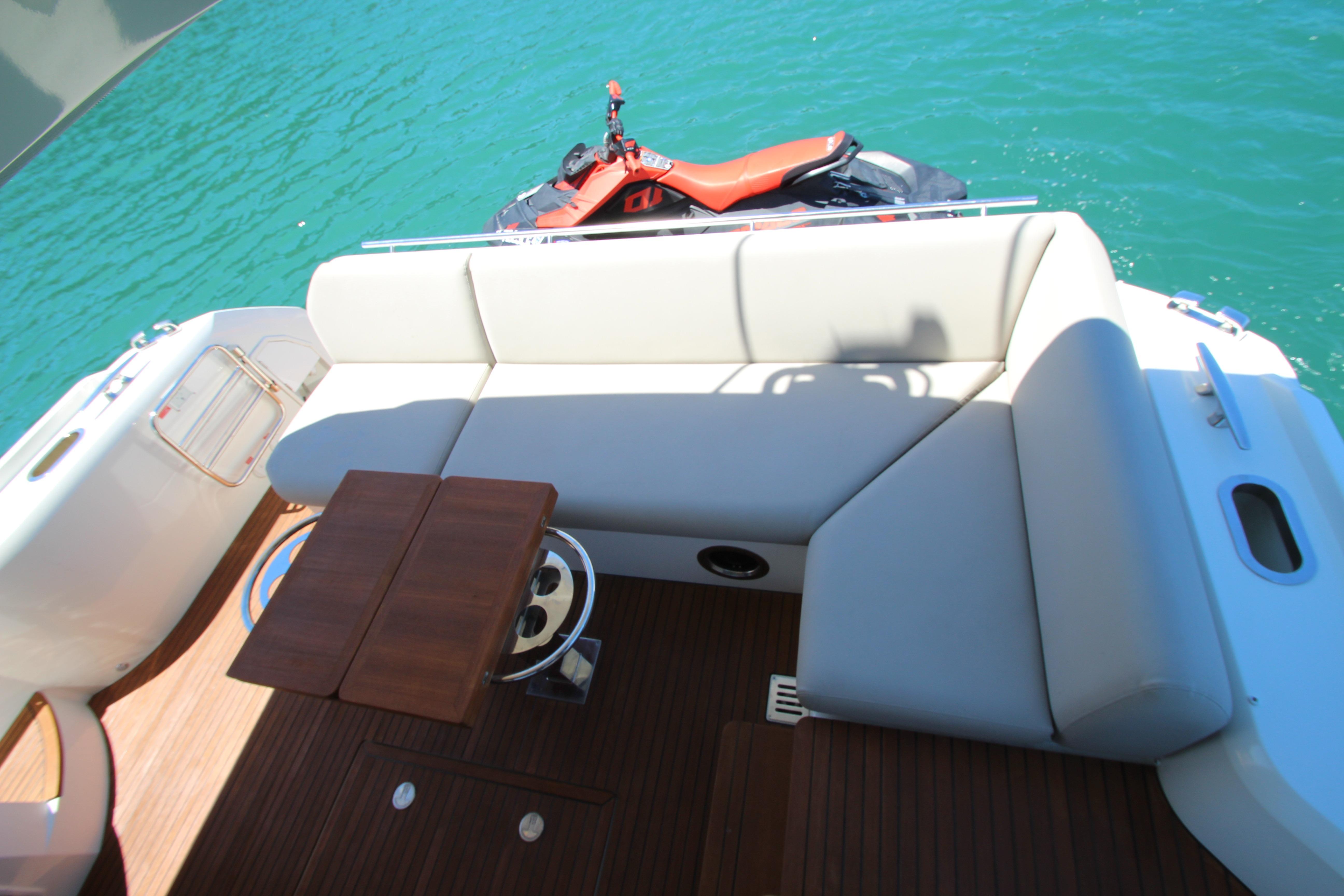 Luxury seating area on 2022 Prestige 520 yacht with watercraft in background.