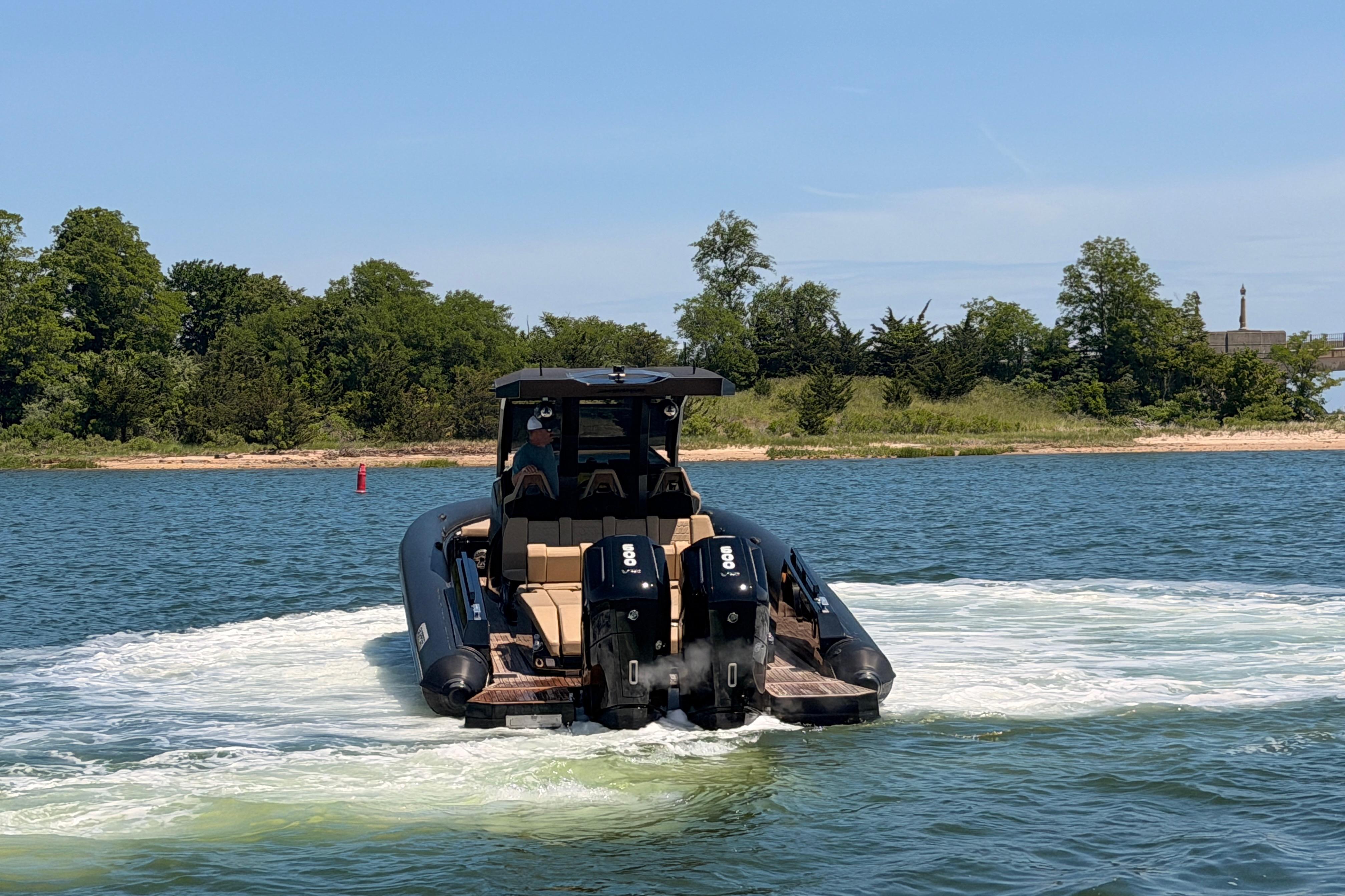 2023 Skipper-BSK 42NC boat cruising on a lake with lush green shoreline.