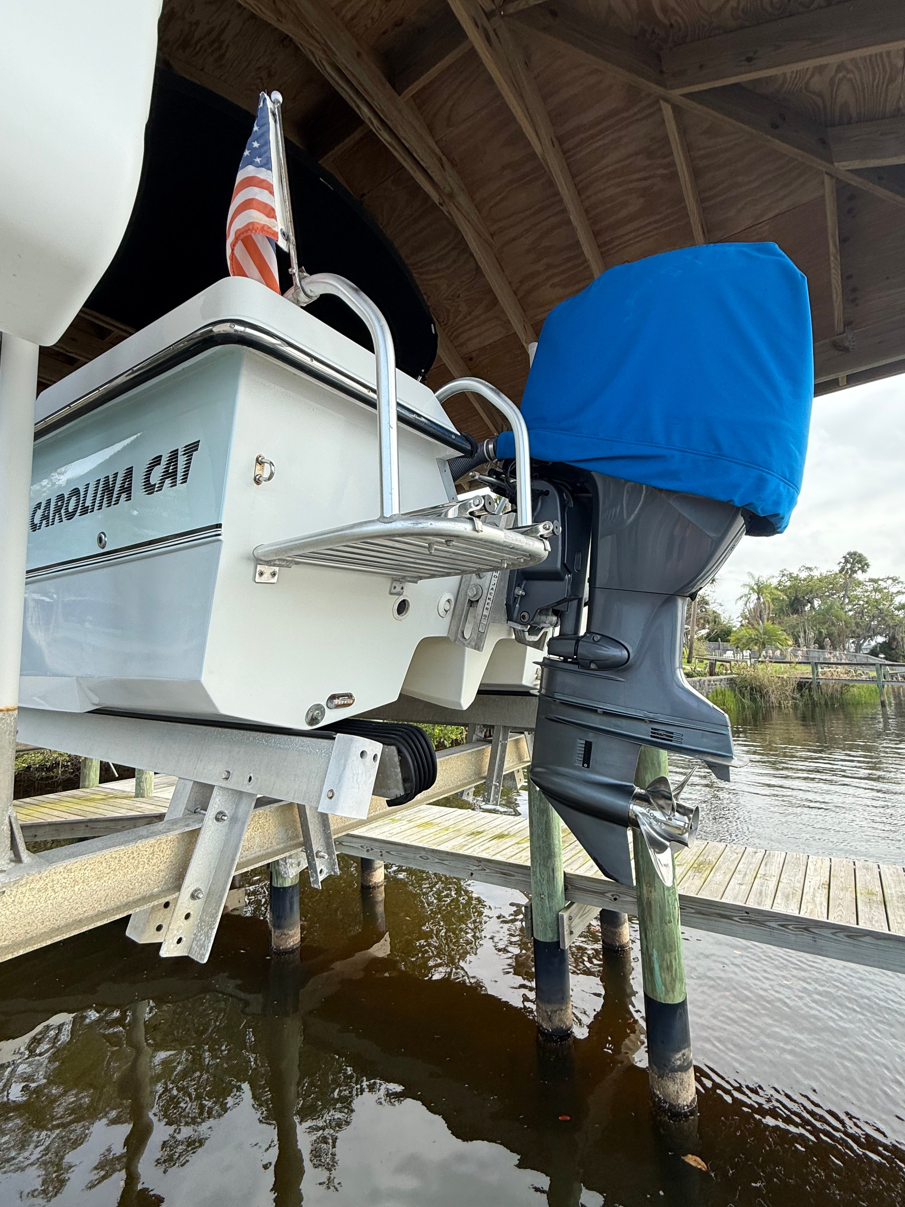A 2011 Carolina Cat 18CC boat is on a lift above the water. It features an outboard motor.