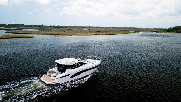 2022 Bavaria SR41 yacht cruising on a serene lake under a cloudy sky.