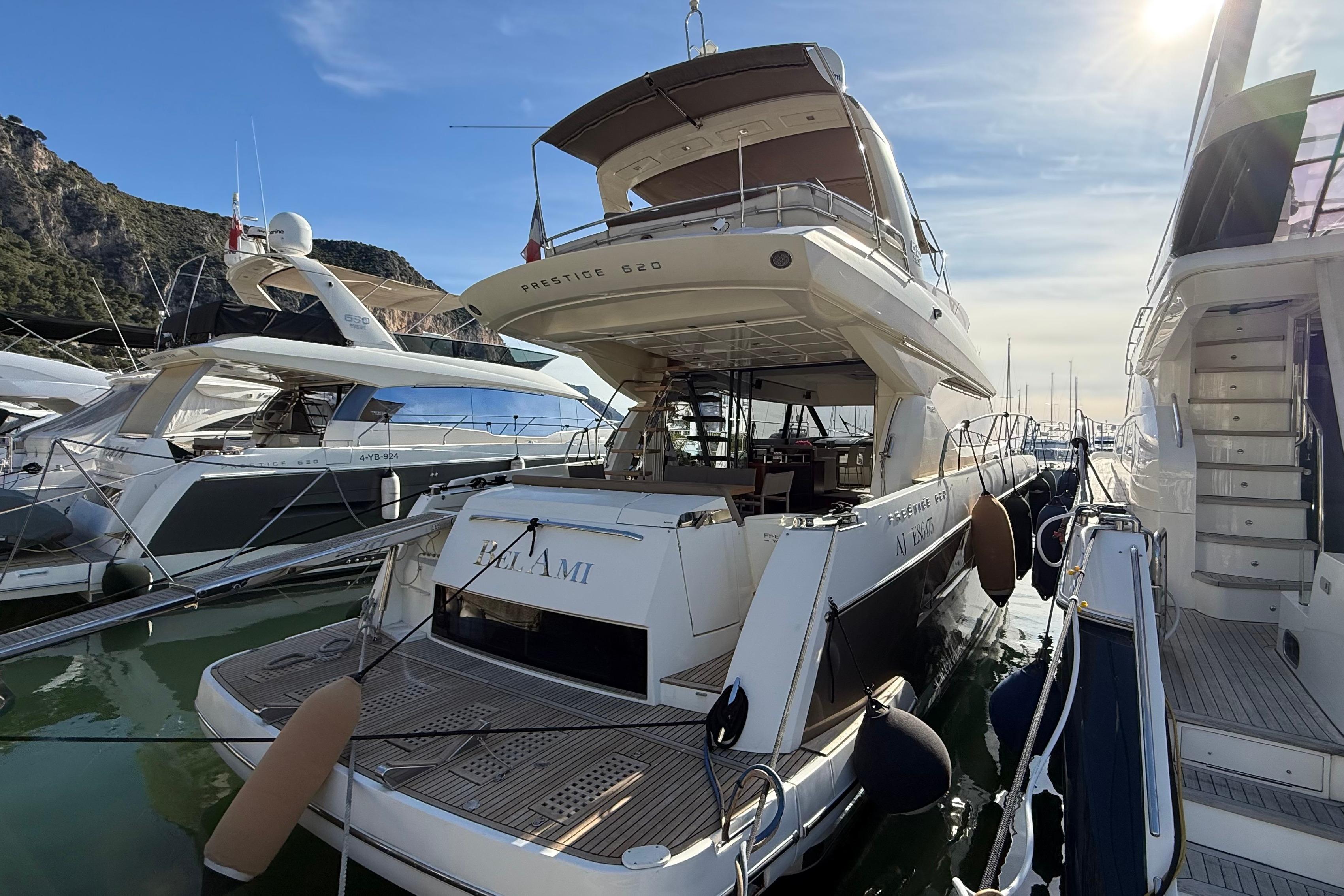 Luxury yacht Prestige 620, 2013 model, docked in a marina under a clear blue sky.