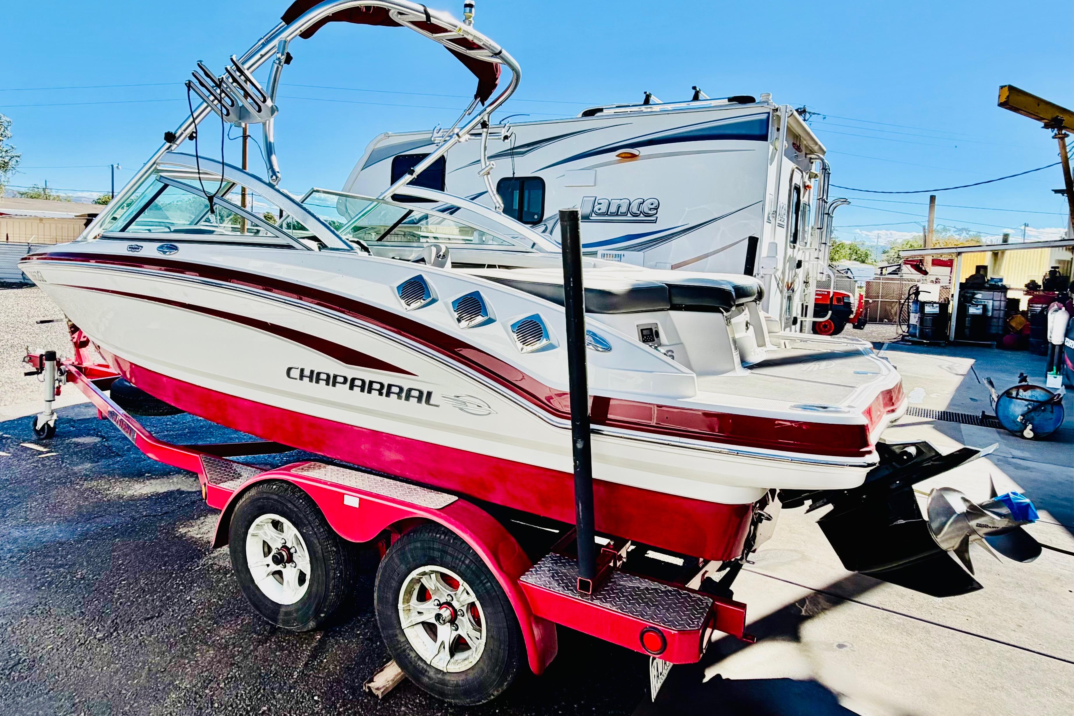 2013 Chaparral 206 SSi boat on trailer, parked outdoors, with a clear blue sky.