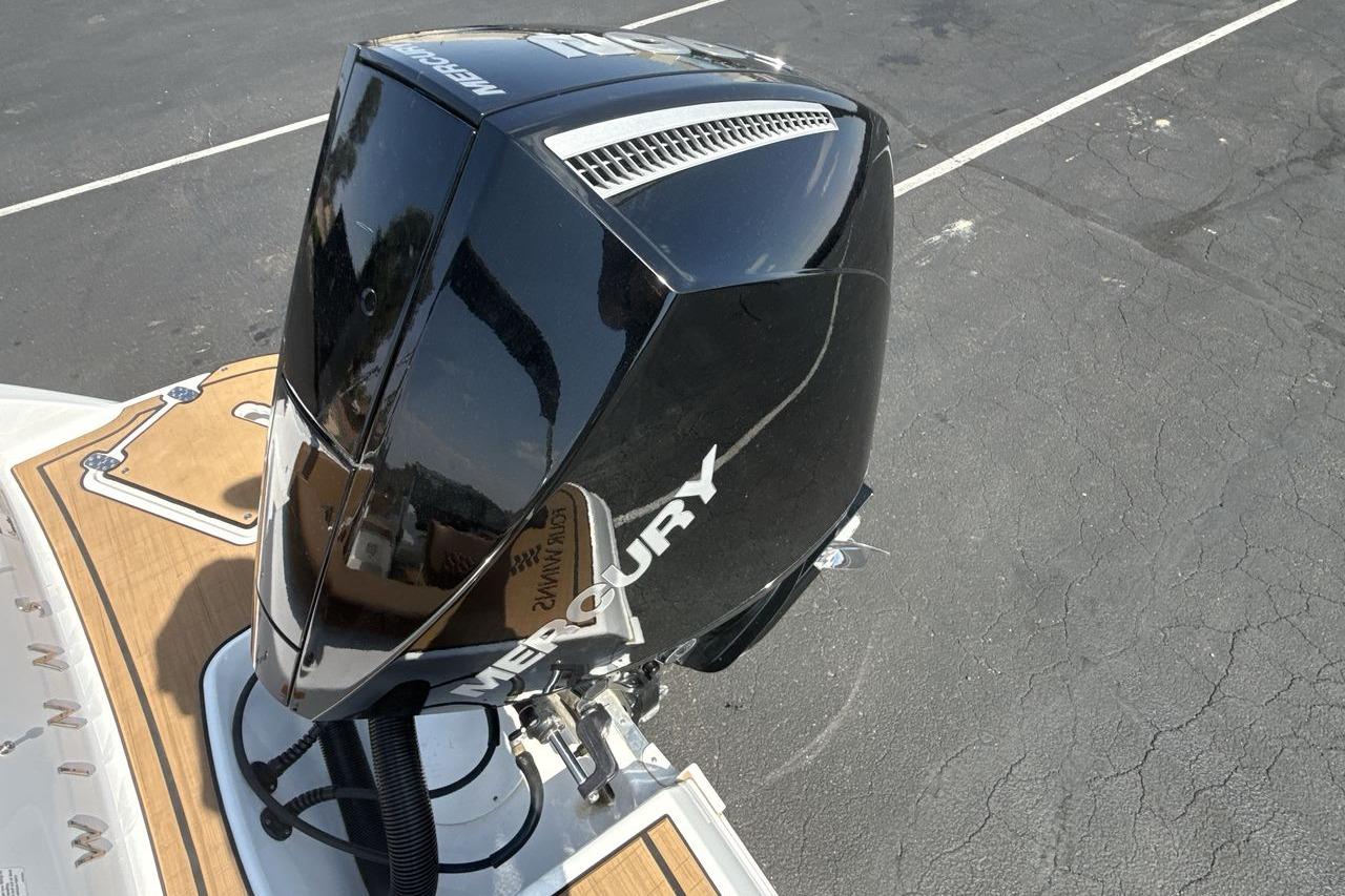 2024 Four Winns H1 OB with Mercury outboard engine, parked on asphalt.