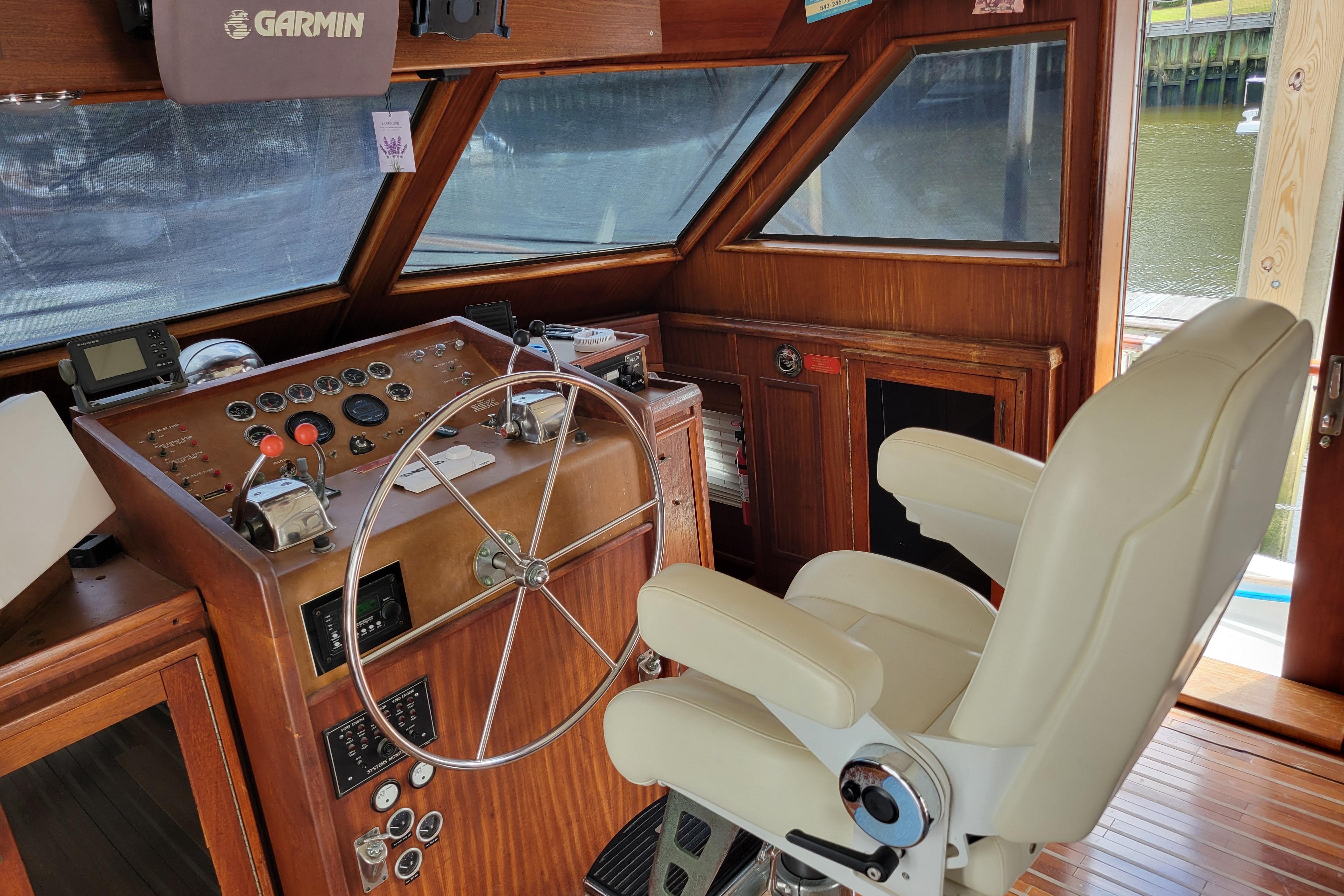 1980 Hatteras 53 Yacht Fisherman helm with steering wheel, controls, and navigation equipment.