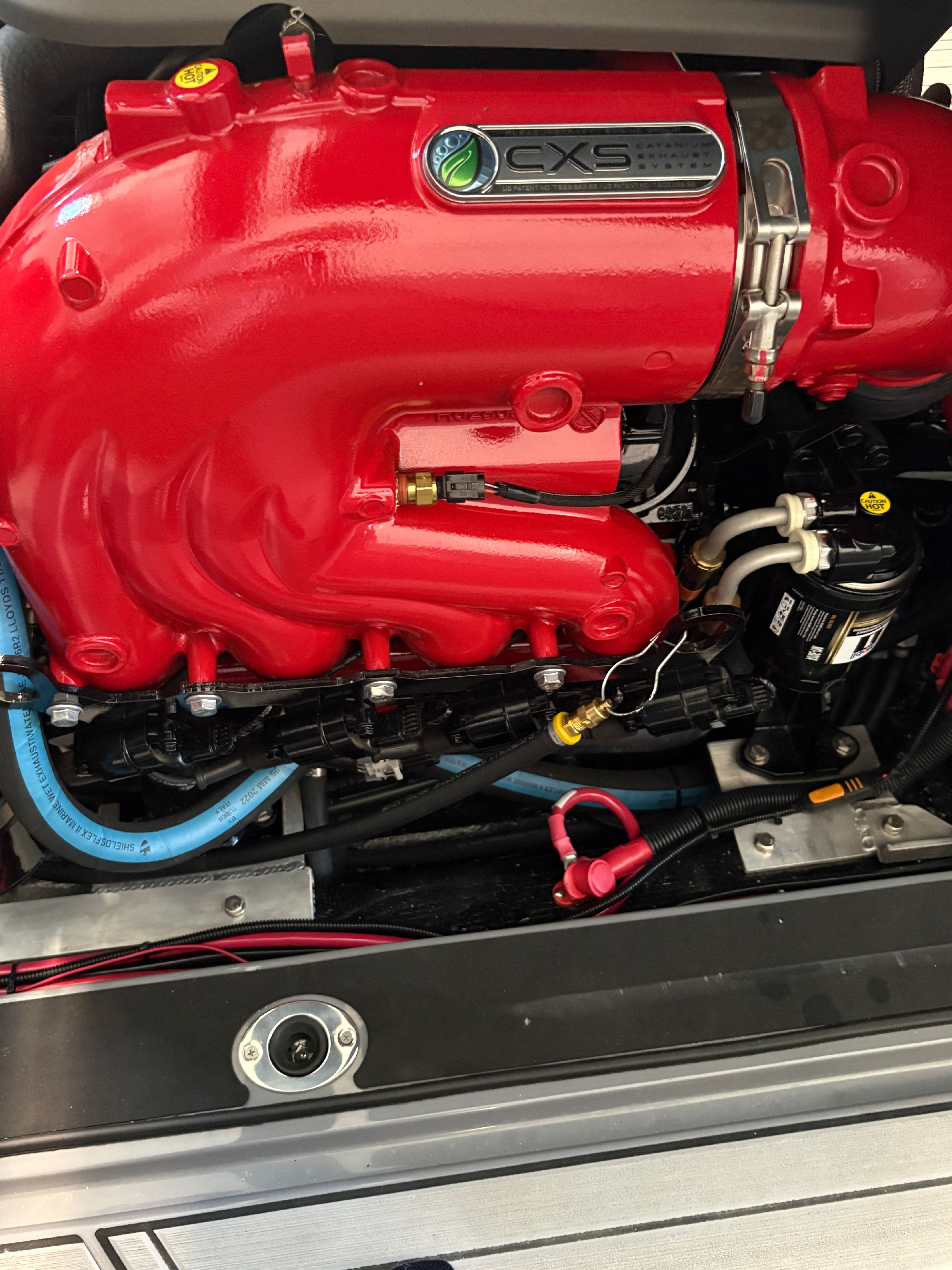 Close-up of a bright red boat engine with various hoses and connections.