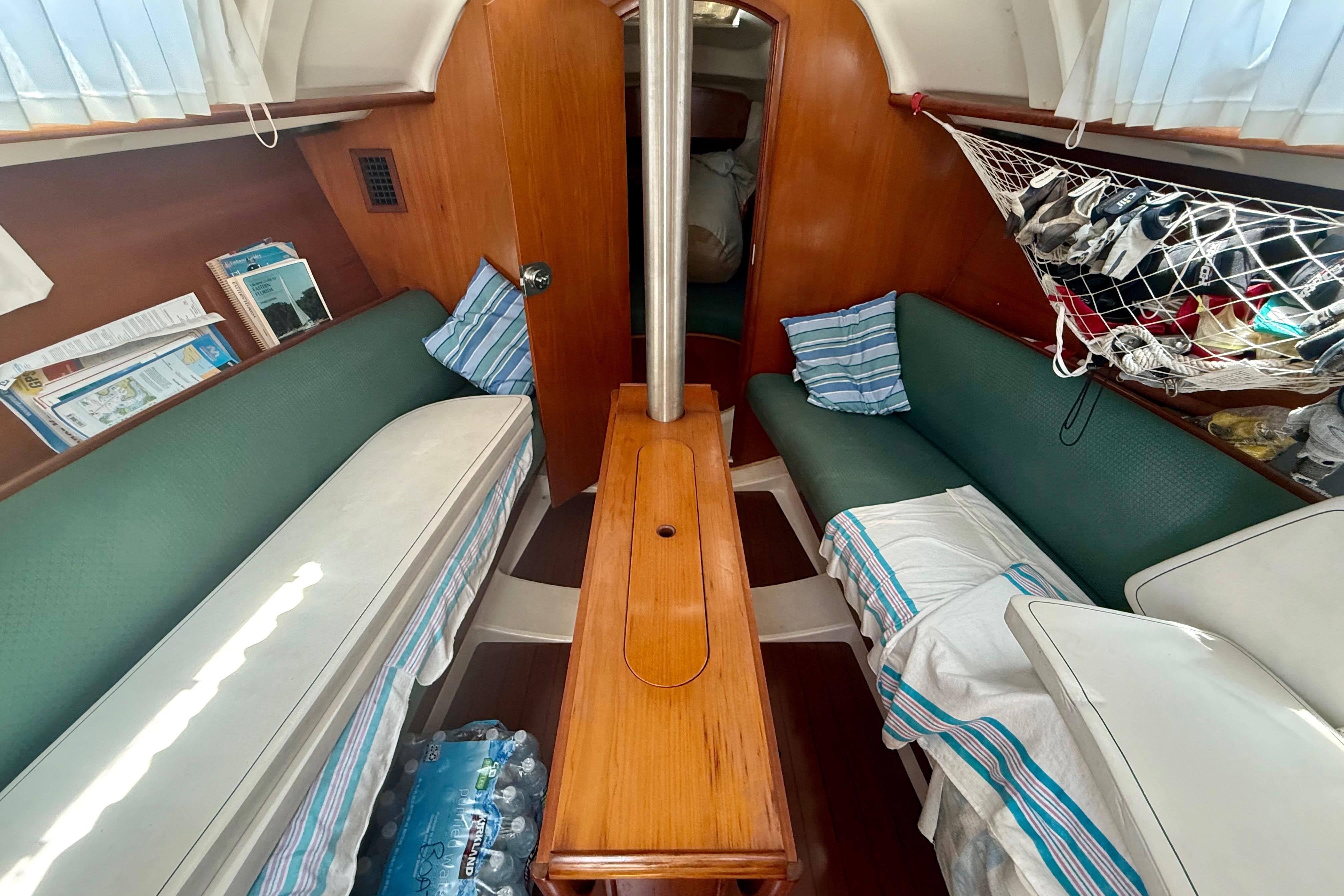 Interior of 2002 Beneteau Oceanis Clipper 311 sailboat with green seating and wooden table.