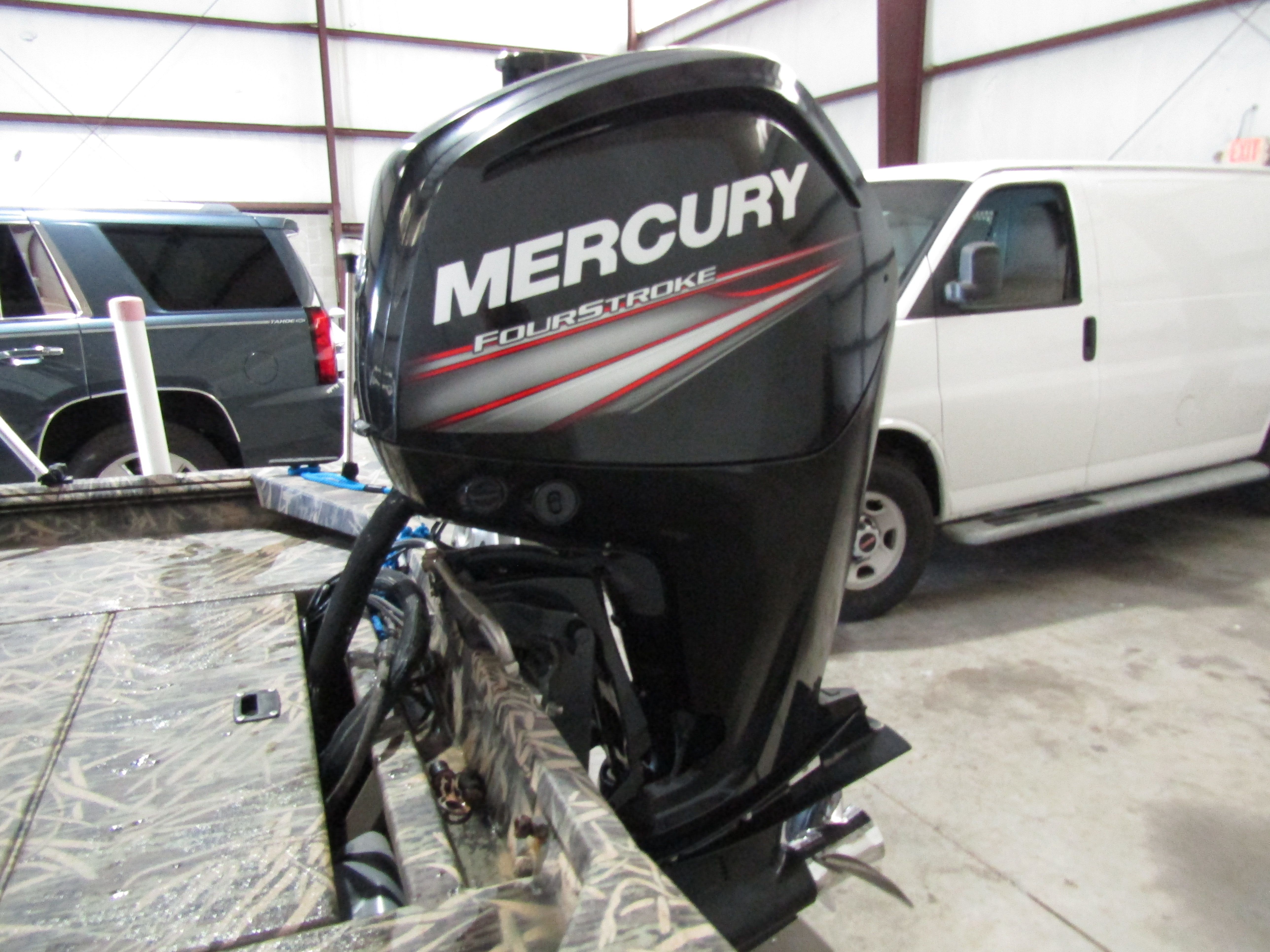 A Mercury FourStroke outboard motor is mounted on a boat inside a garage.