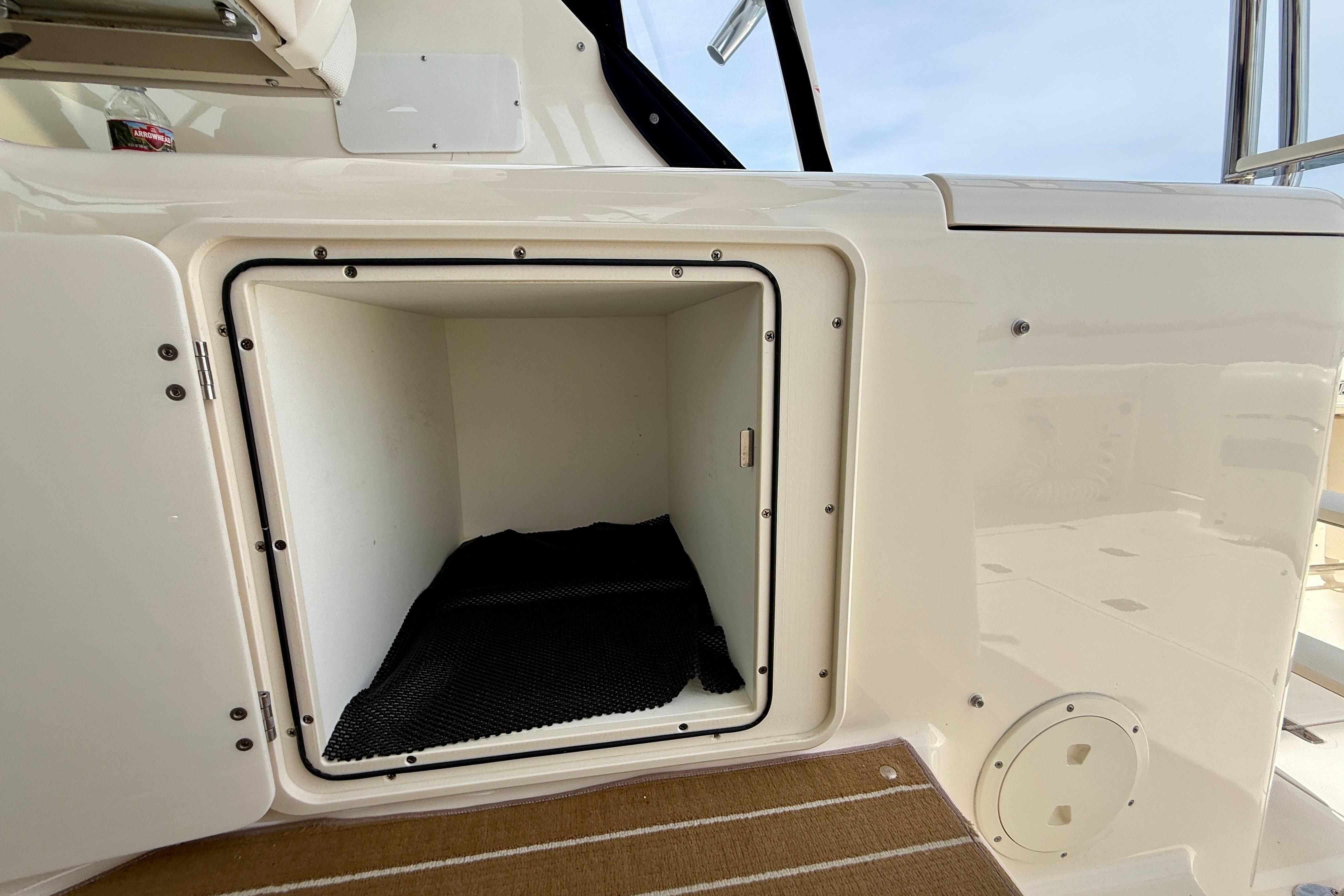 Storage compartment on a 2012 Pursuit OS 345 Offshore boat, open with black mat inside.
