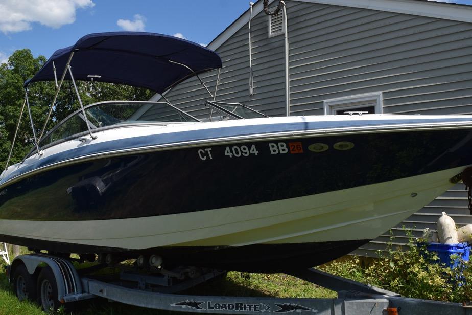2006 Cobalt 240 boat on trailer, parked beside a house under a blue sky.