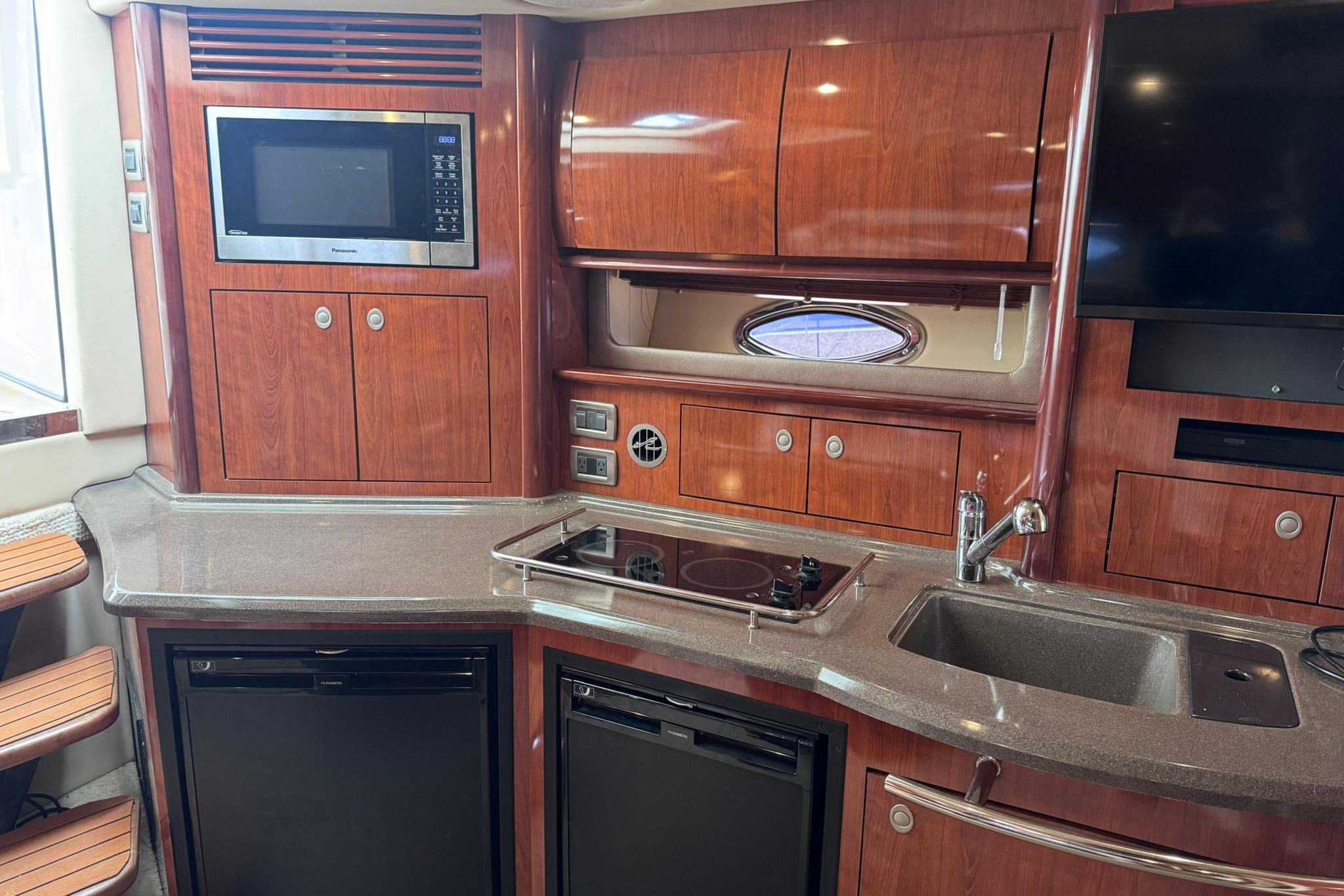 Luxurious 2004 Sea Ray 390 Sundancer yacht kitchen with wood cabinetry and modern appliances.