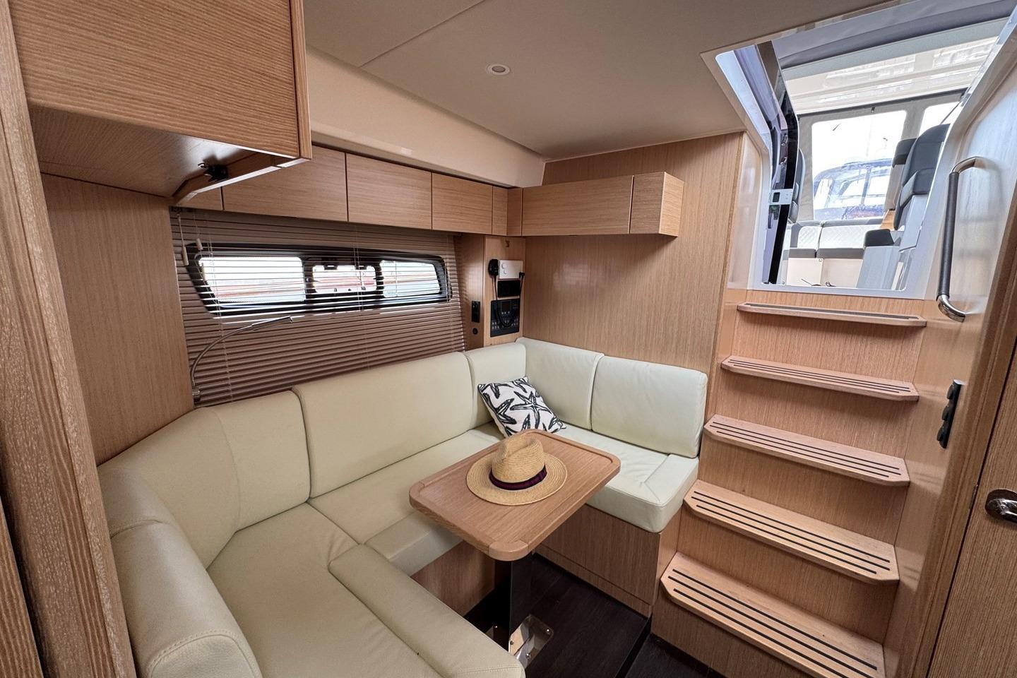 Interior of 2023 Bavaria SR41 yacht with cozy seating and wooden finishes.