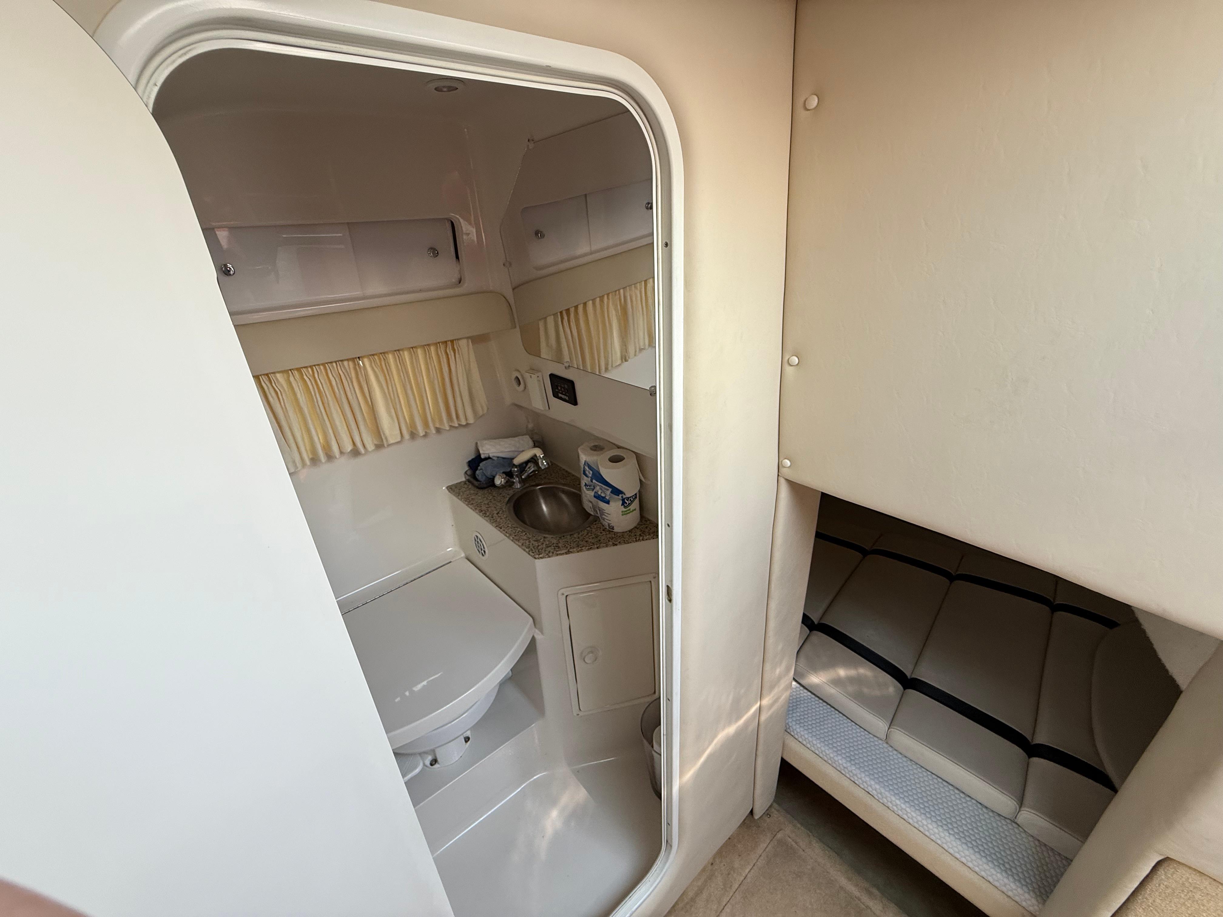 2005 Monterey 290SE boat interior with compact bathroom and cozy sleeping area.