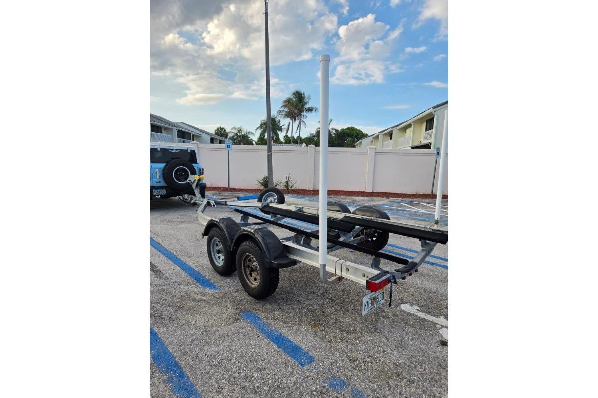 Trailer for 2024 Yamaha Boats 222 FSH Sport E, parked in a lot under a cloudy sky.