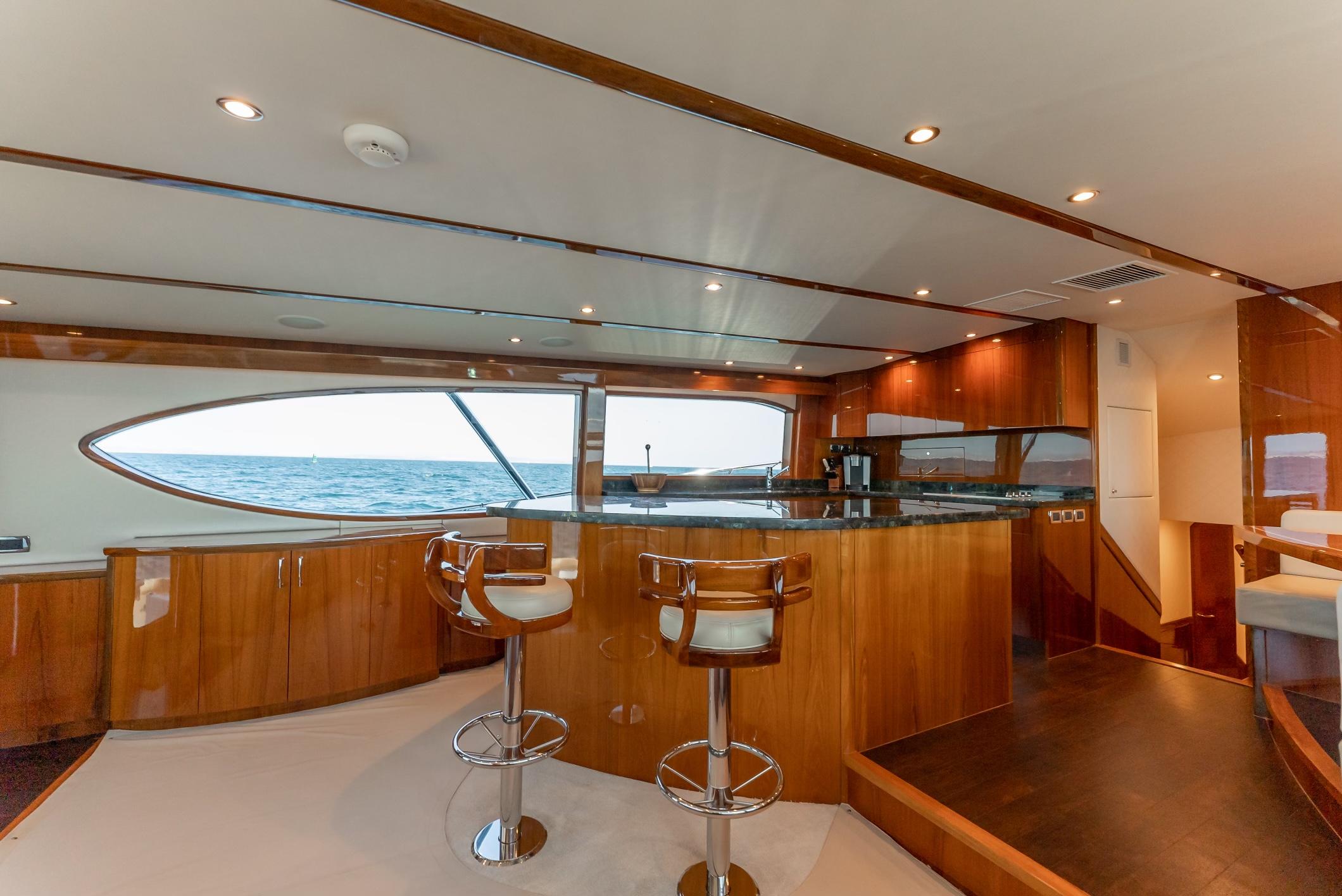 Luxurious interior of 2018 Hatteras GT70 yacht with elegant wood finishes and ocean view.