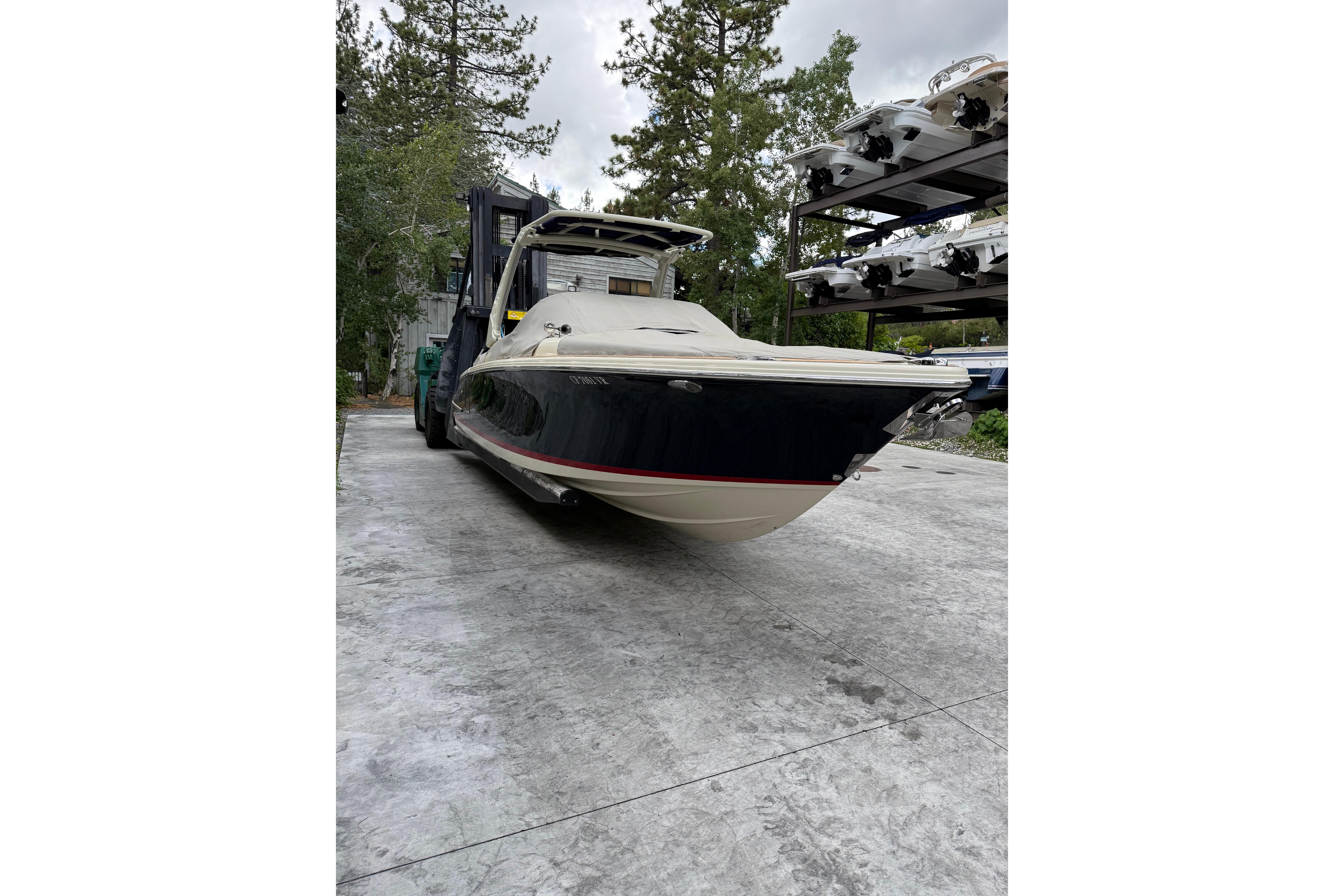 2019 Chris-Craft Launch 28 GT boat on a lift, surrounded by trees and other boats.