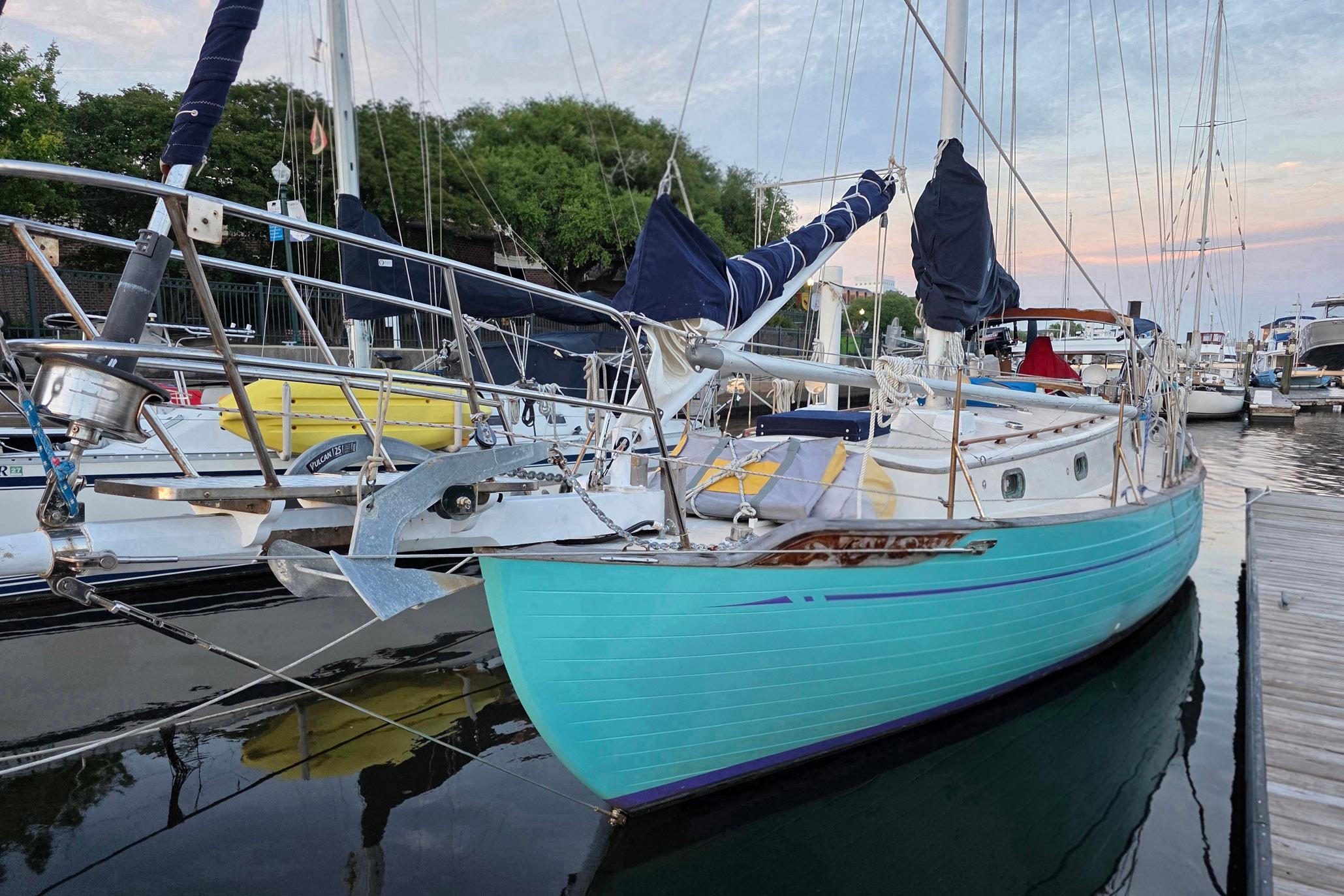 A 1982 Tayana 37 sailboat docked, featuring a turquoise hull and classic design.