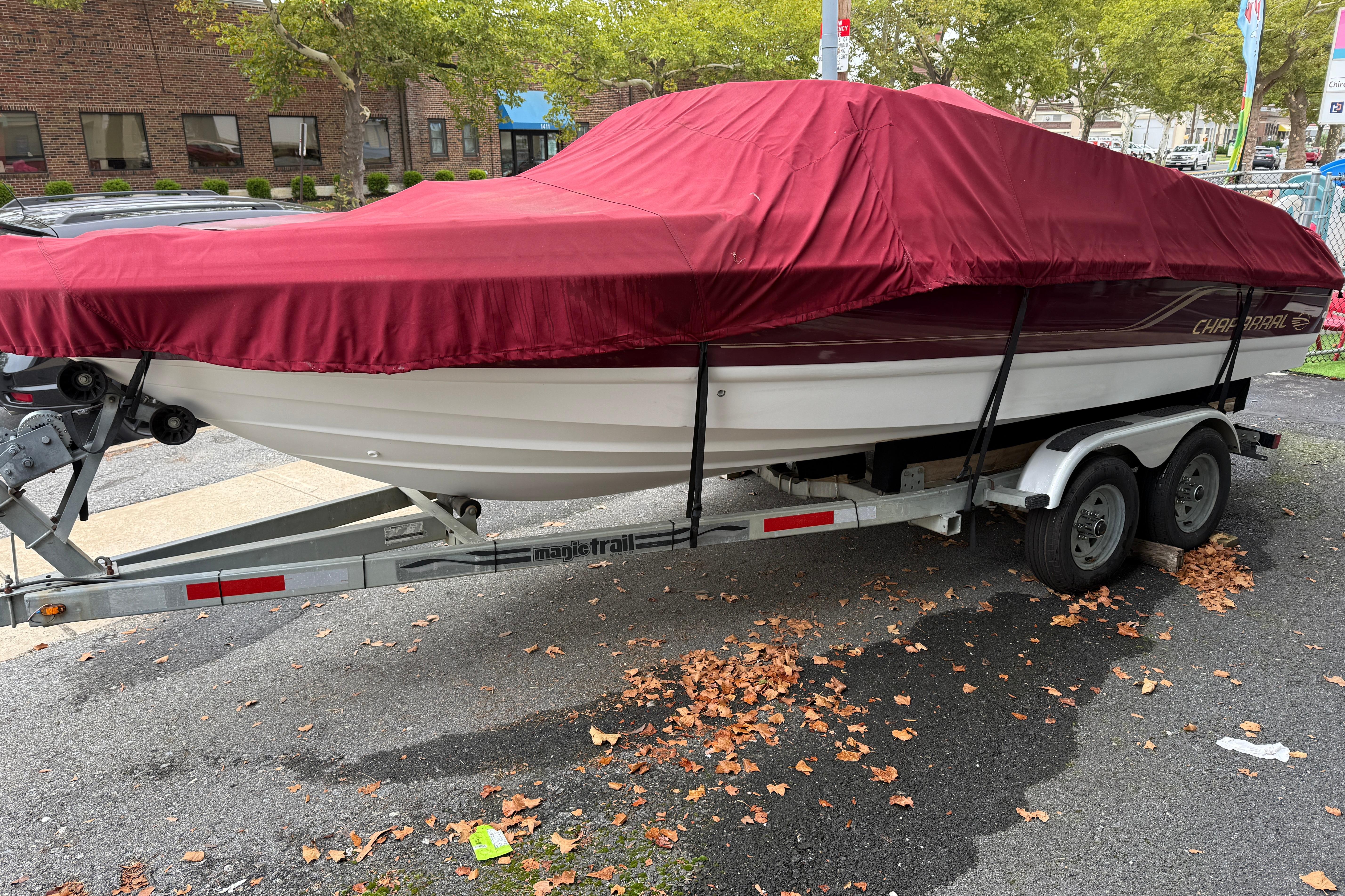 Covered 1999 Chaparral 1930 SS boat on trailer, parked on street with autumn leaves.
