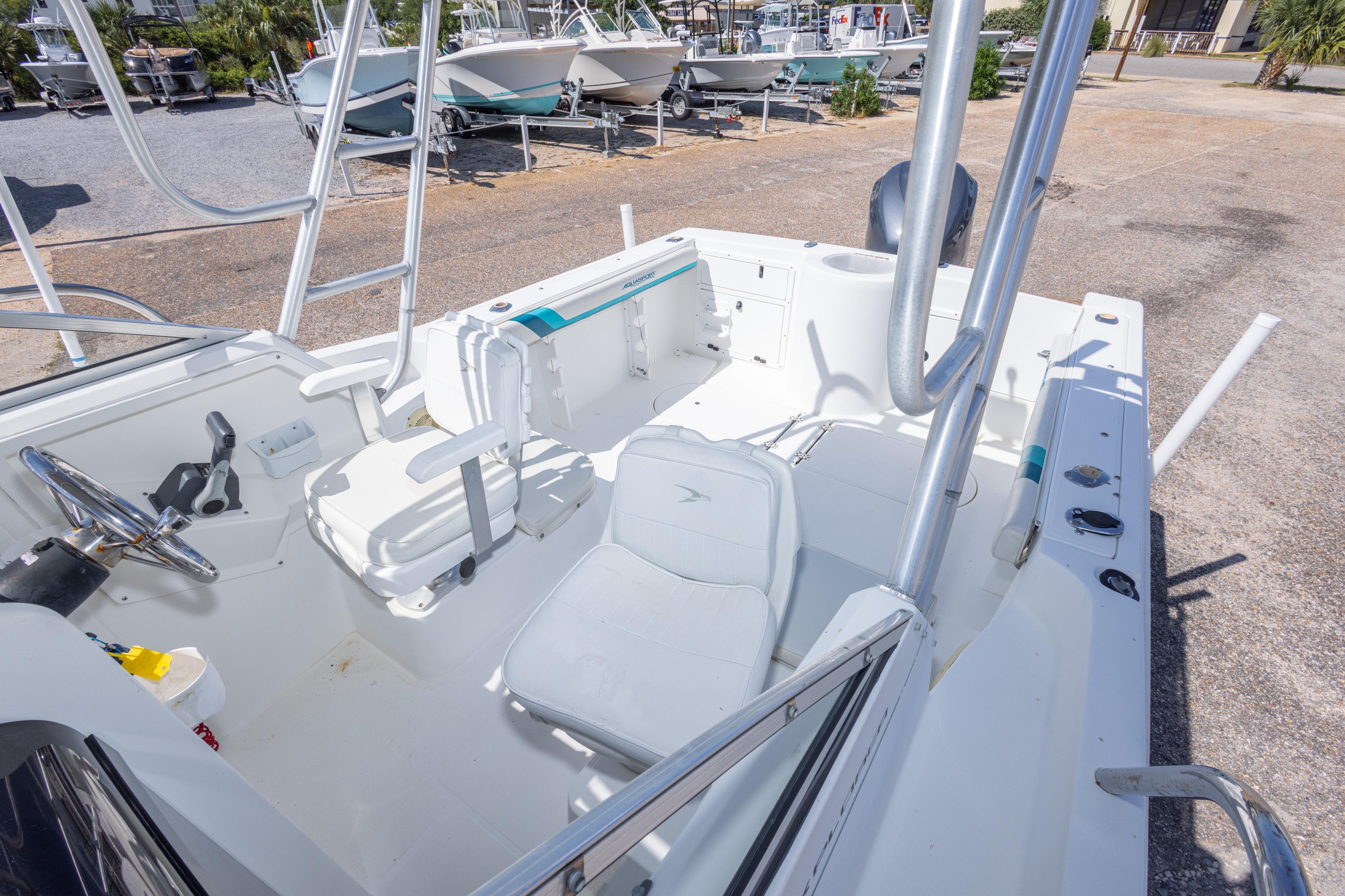 1999 Aquasport 225 Explorer boat interior with seating and steering wheel, parked outdoors.