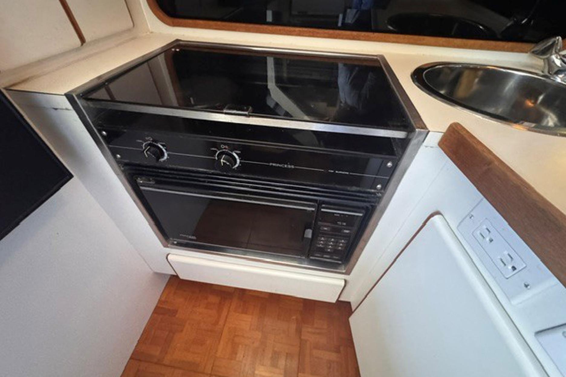1988 Tiara Yachts 3300 Open kitchen with stove and sink in compact galley.