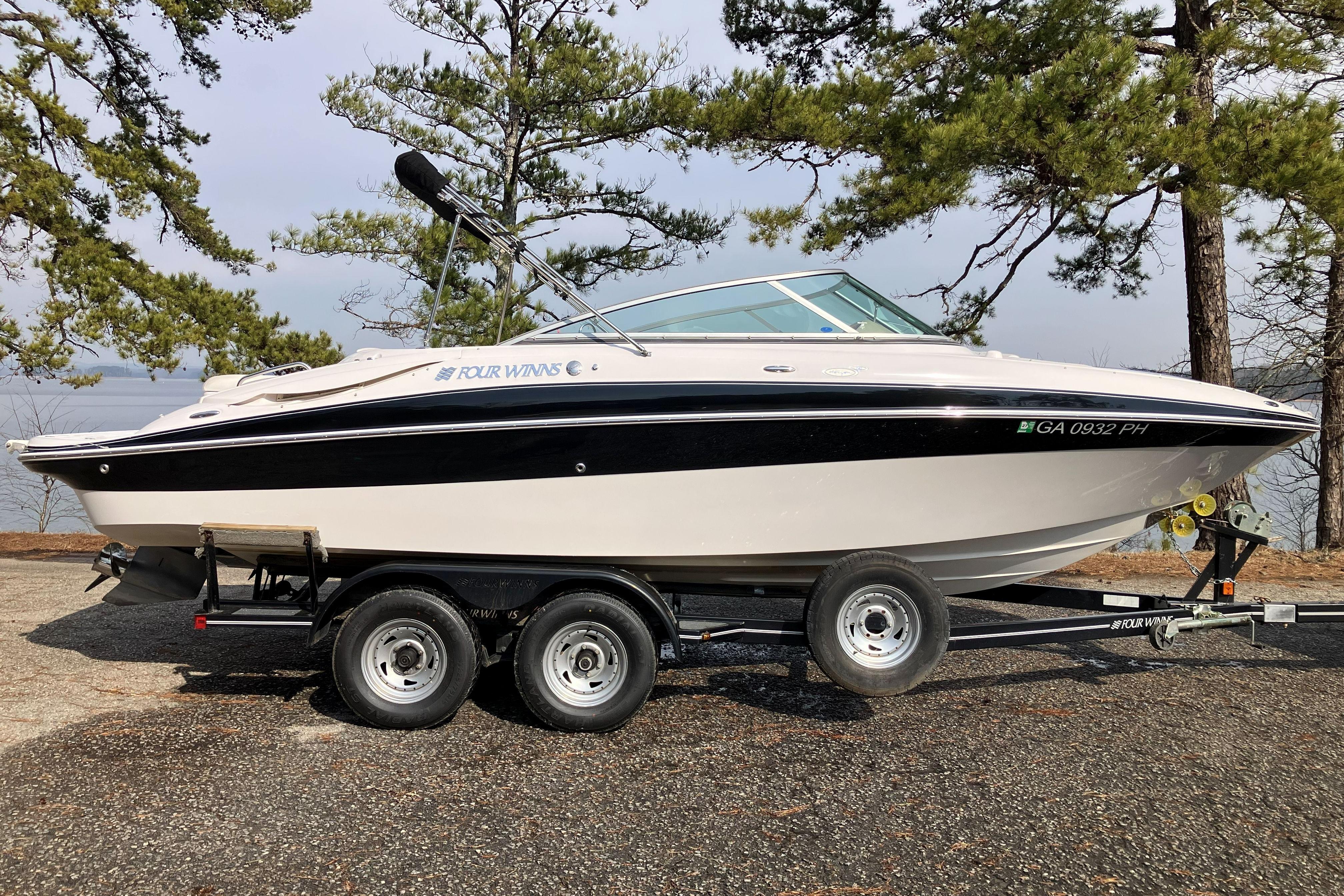 2006 Four Winns 240 Horizon boat on trailer, parked near trees and water.