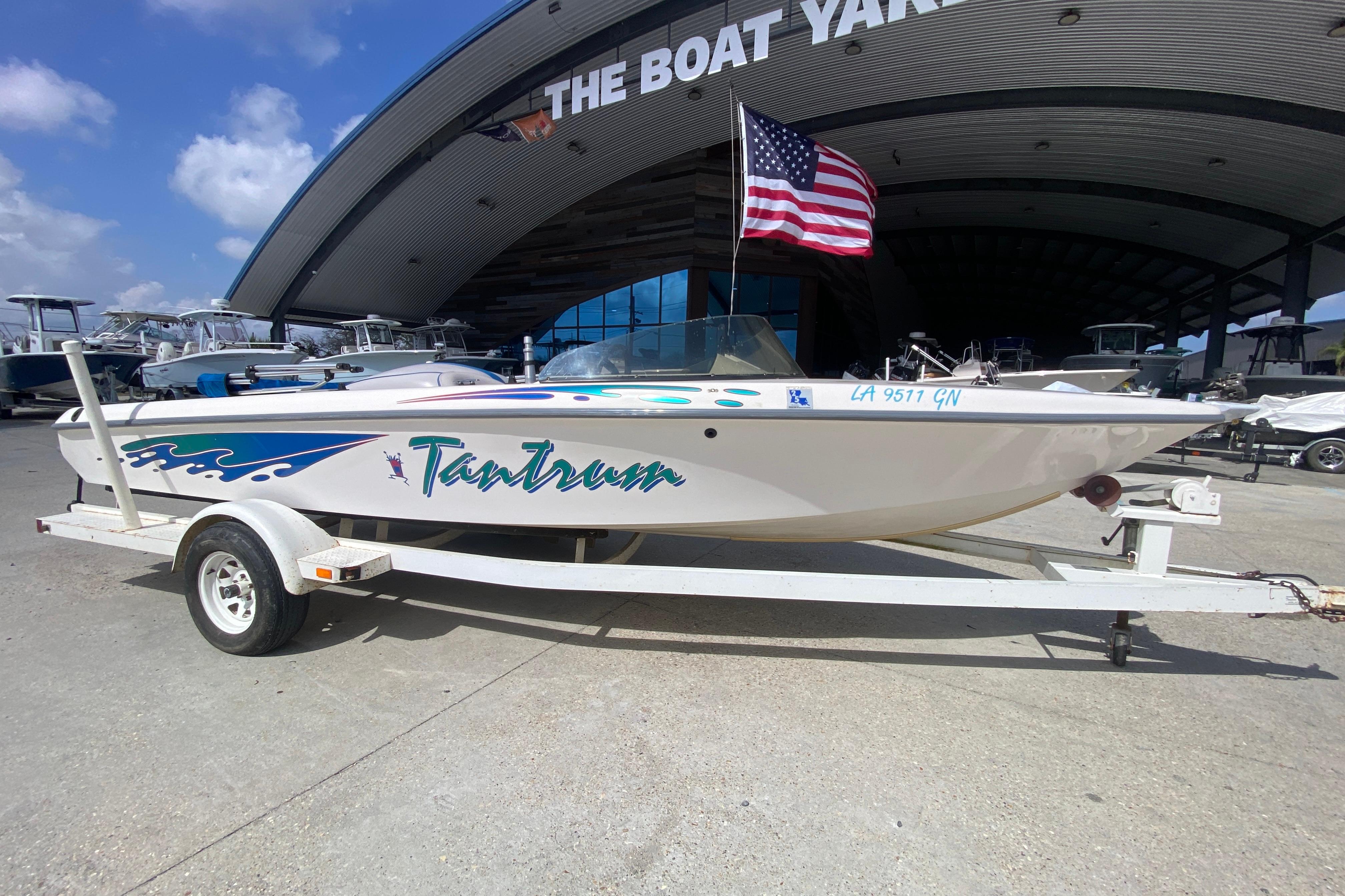 1997 Malibu Tantrum boat on trailer with American flag, parked at The Boat Yard.