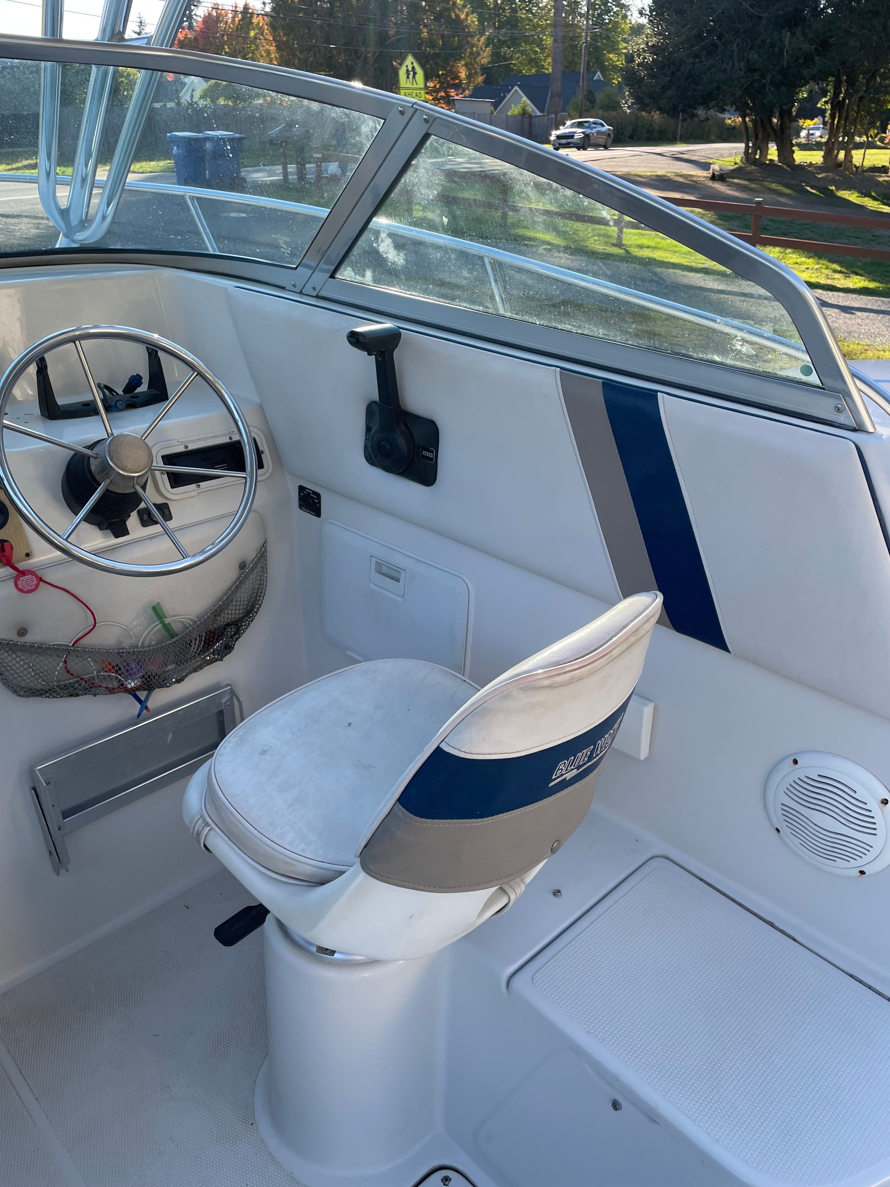 The image shows the cockpit of a 2001 Bluewater 2100 sport fisher. It features a white seat and steering wheel.