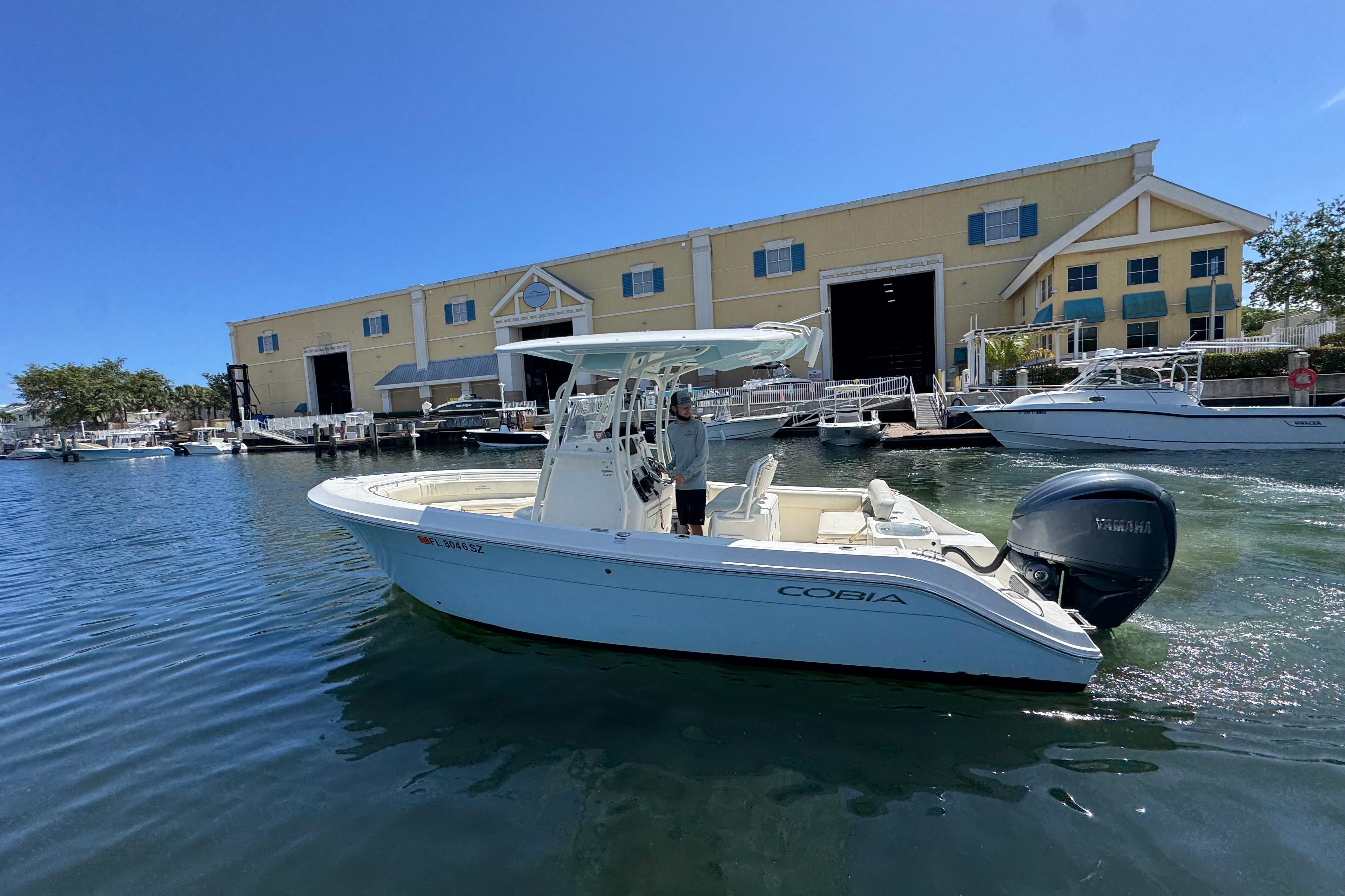 2021 Cobia 237 Center Console boat docked near a marina building.