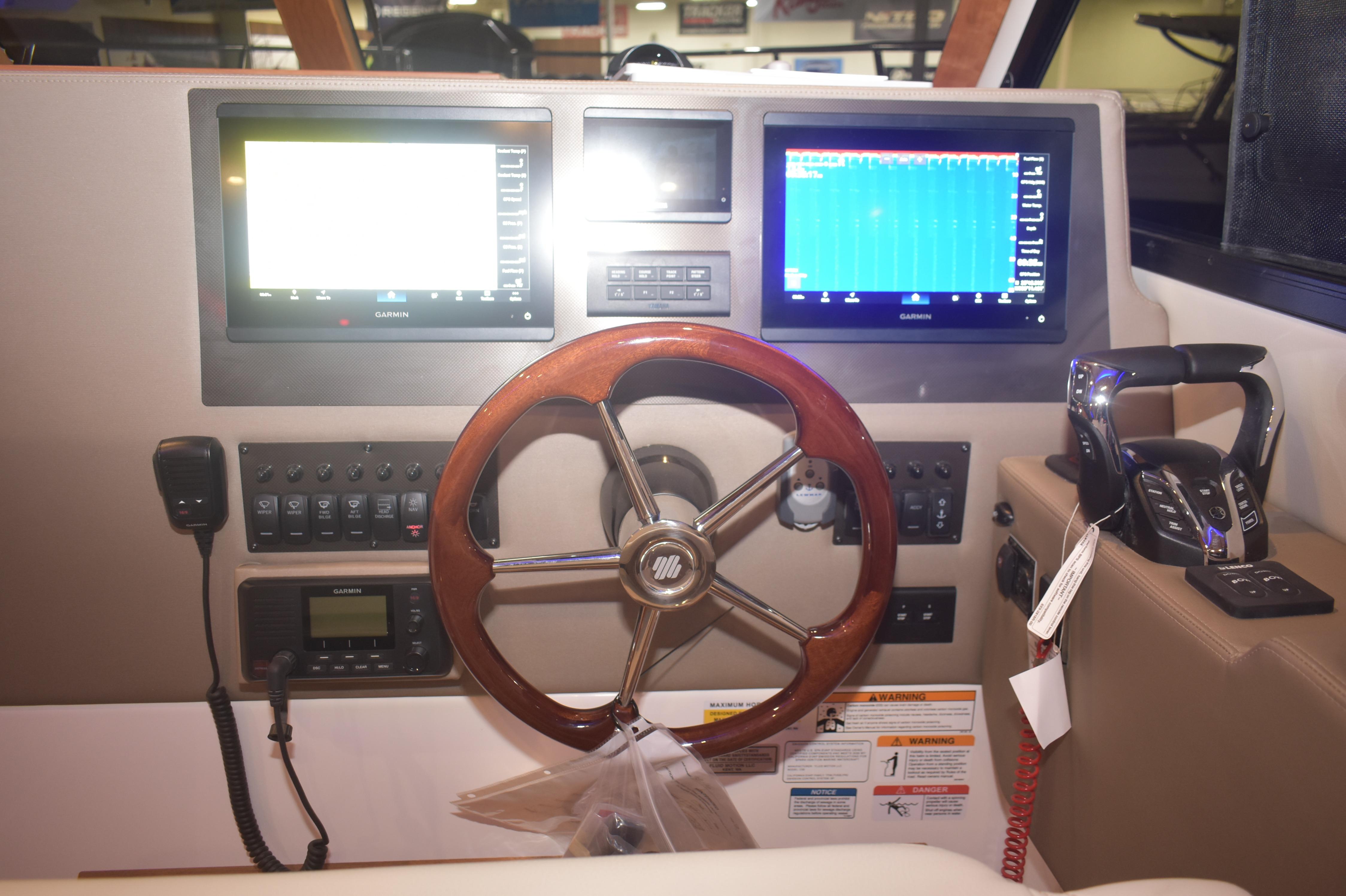 Helm of 2026 Cutwater C-32 CB with dual Garmin displays and wooden steering wheel.