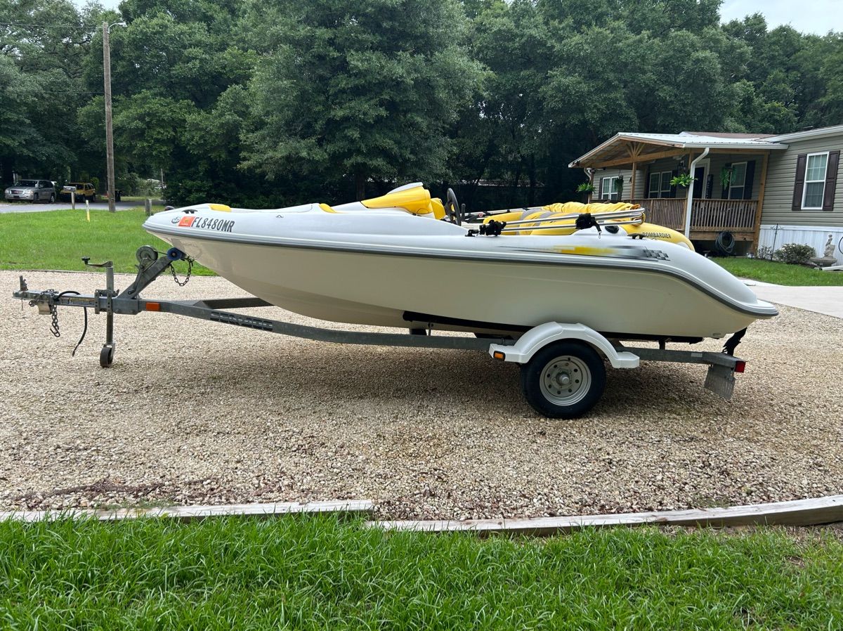A white 2004 Sea-Doo Sportster LE DI boat on a trailer in a gravel area.