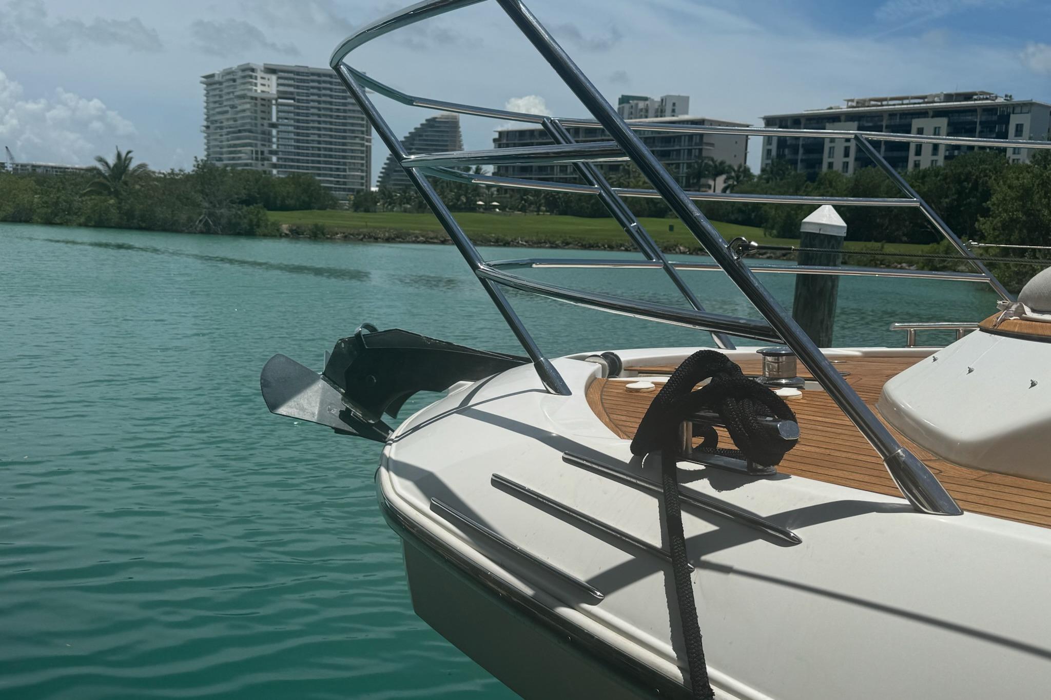 Azimut 55 yacht docked on turquoise water, modern buildings in background, sunny day.
