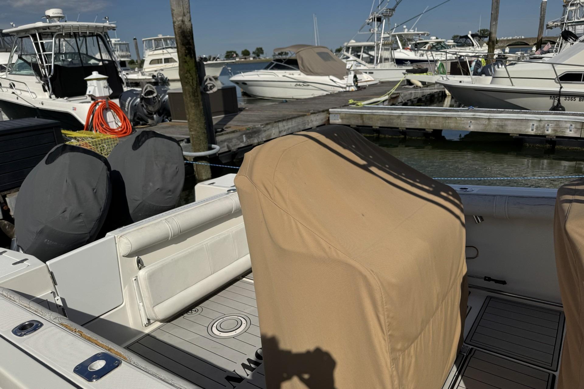 2007 Edgewater 245CC boat docked at marina with covered seats and engines.