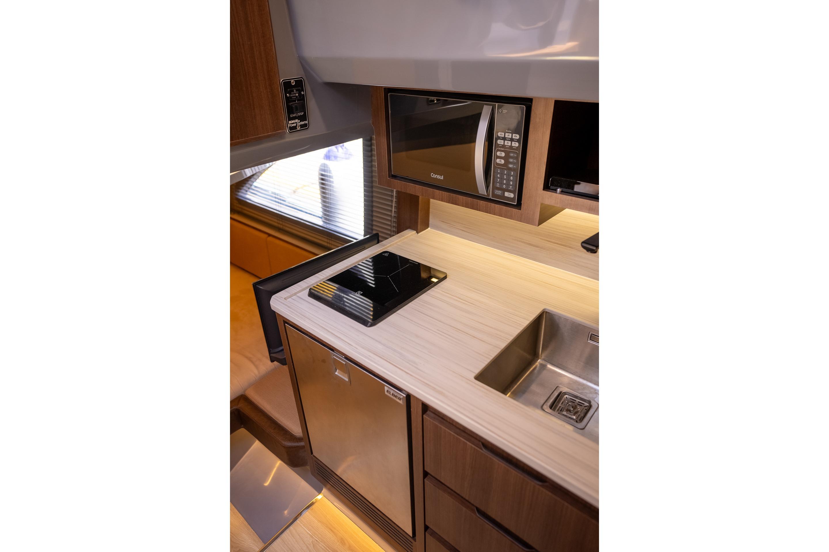 Modern kitchen interior in 2026 Hanover 447 RV with microwave, sink, and induction cooktop.