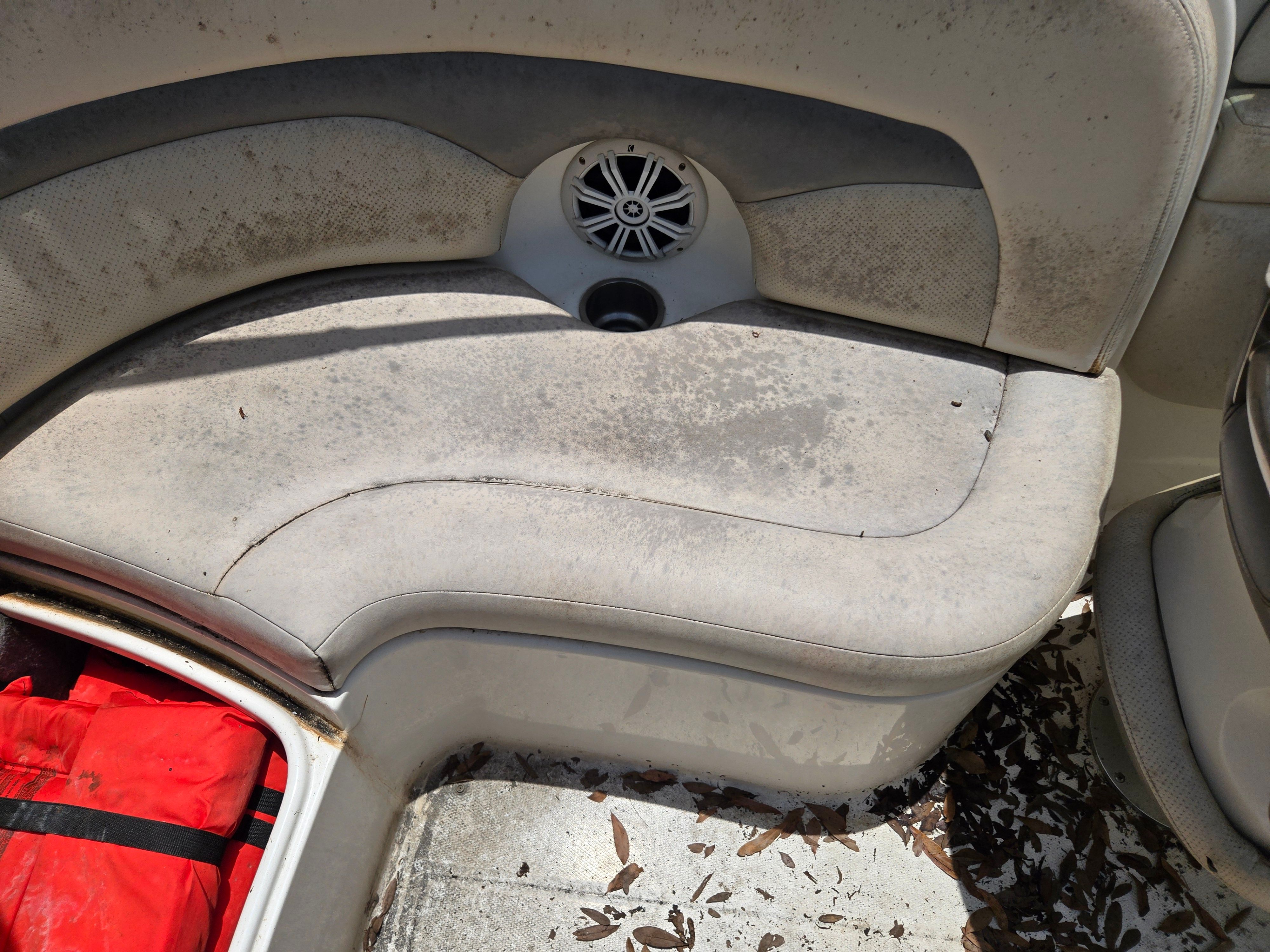 A used boat with worn seats and leaves scattered on the floor.
