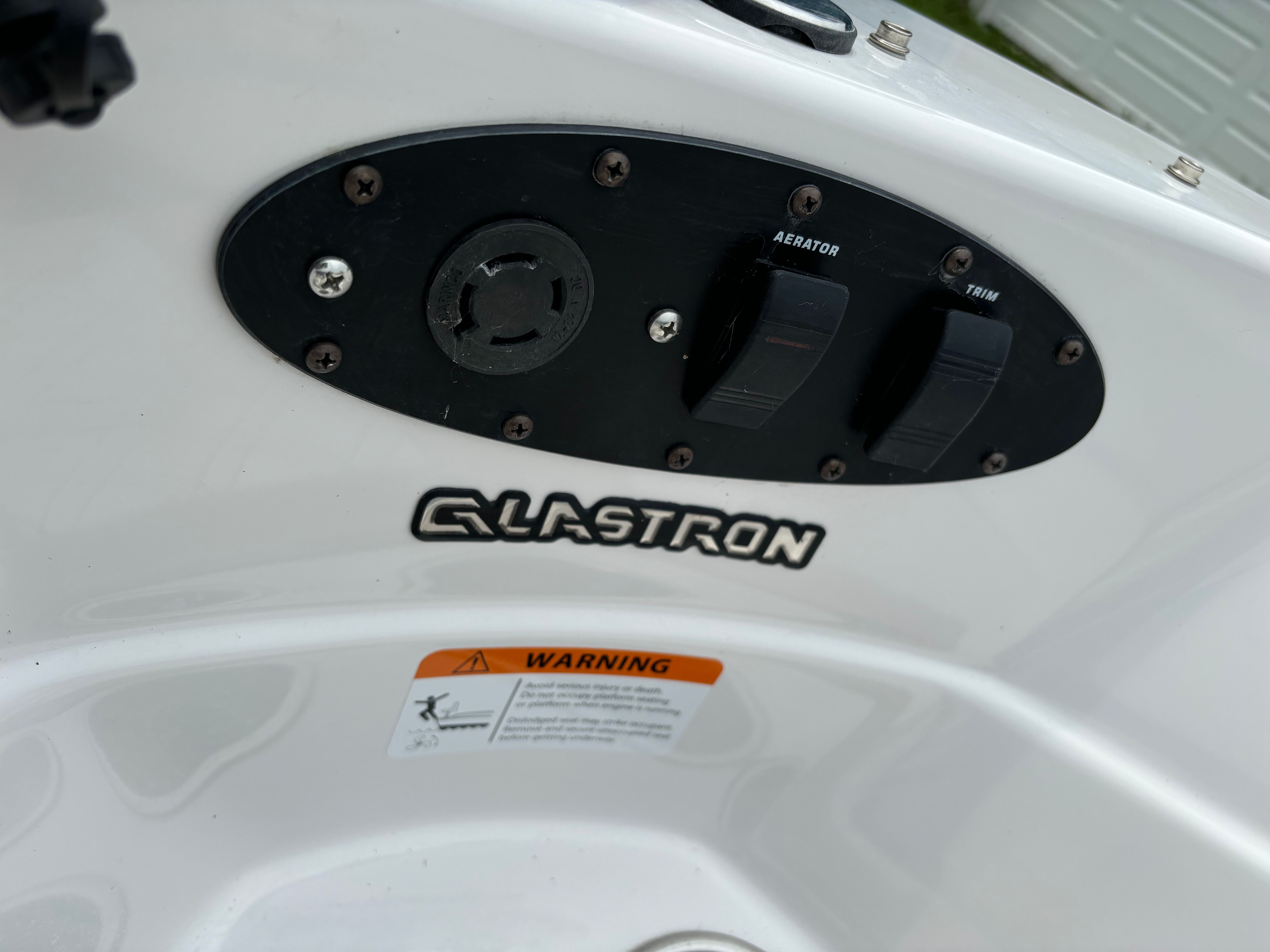 Close-up of a Glastron boat's control panel with switches and a warning label.