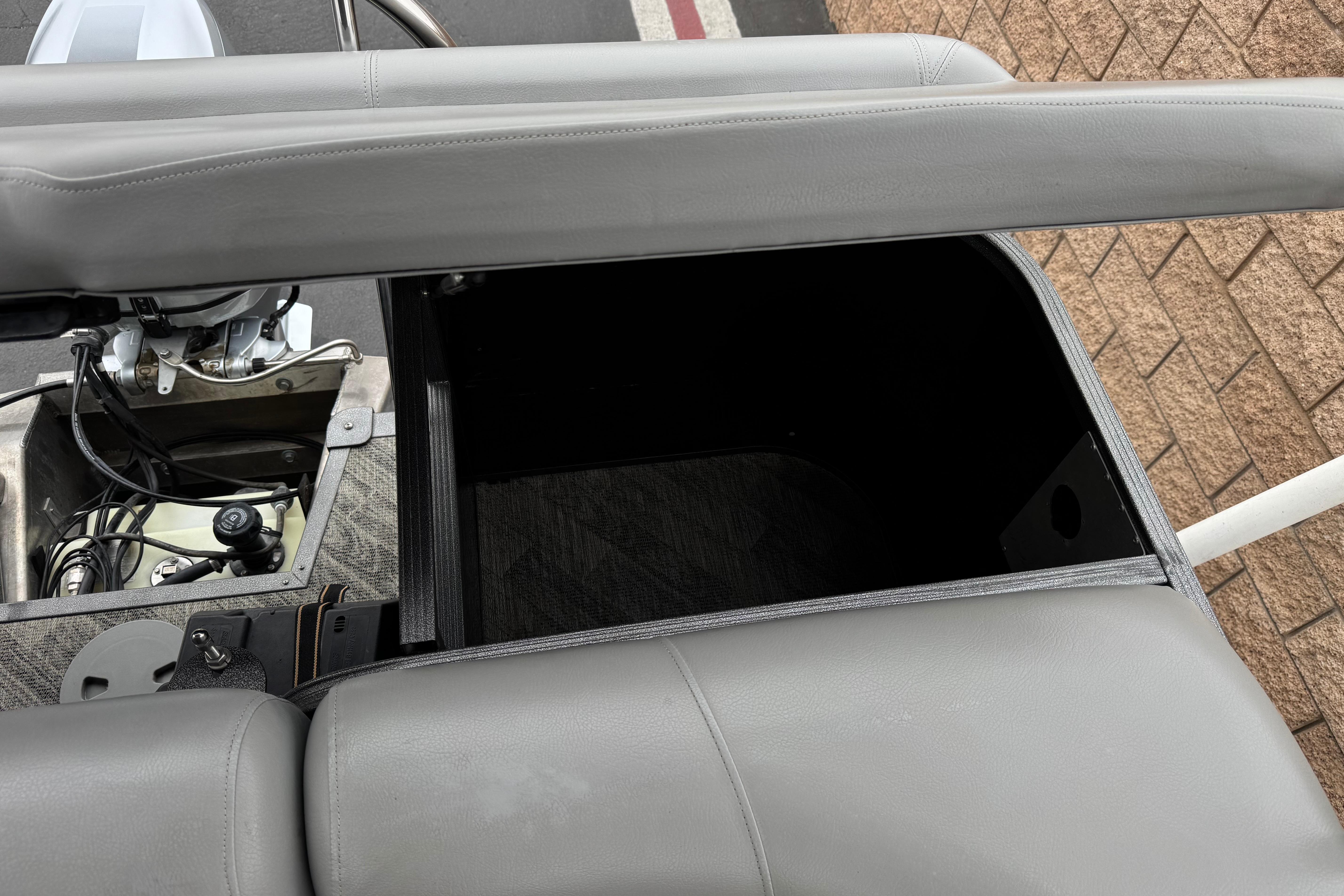 Open storage compartment in 2020 Manitou 18 Aurora LE pontoon boat with visible engine components.