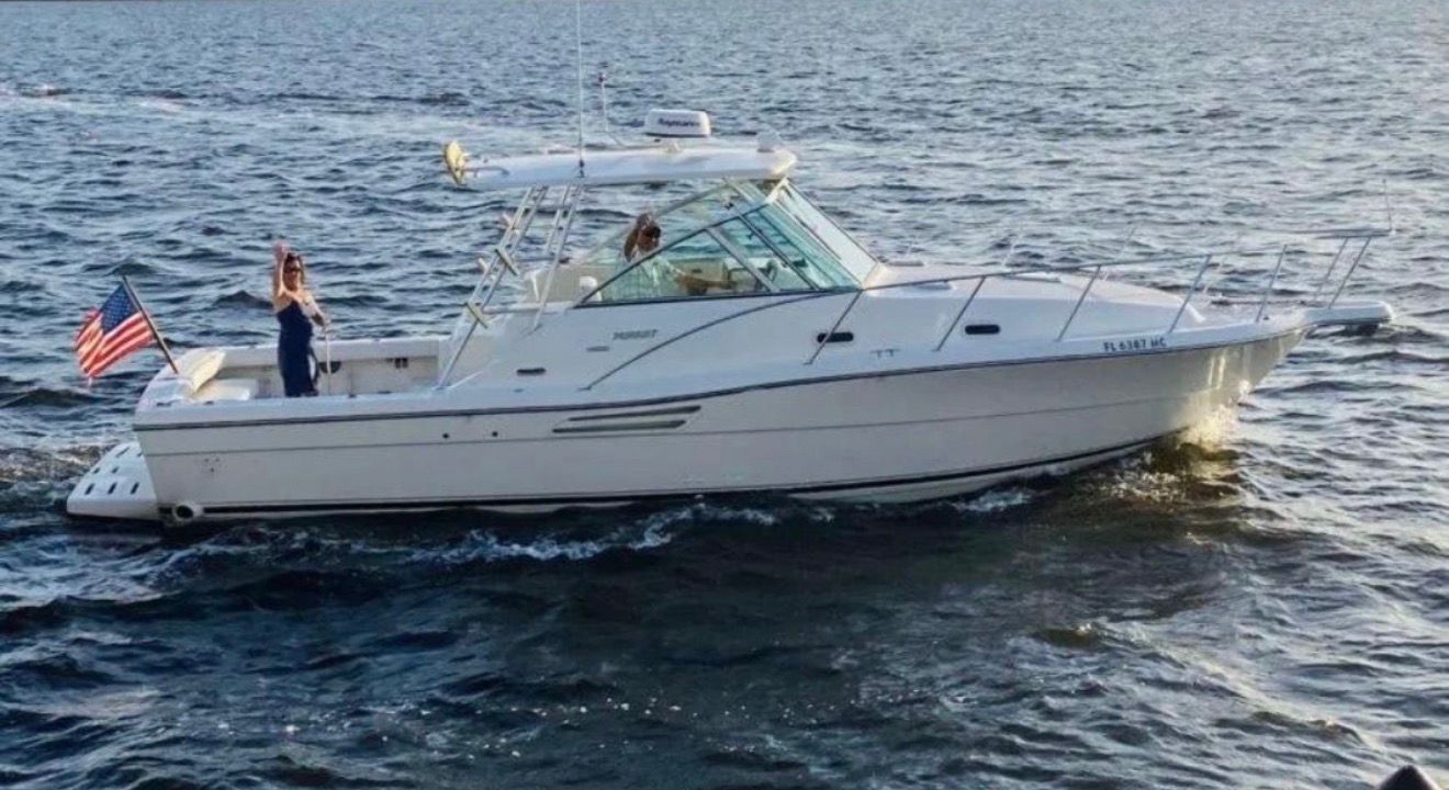 A white boat cruising on the water, with an American flag at the stern.