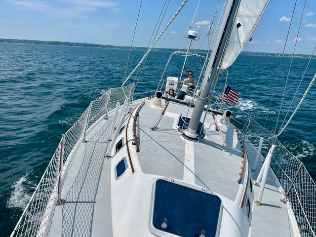 A 1989 Catalina 34 sailing on open water under a blue sky.
