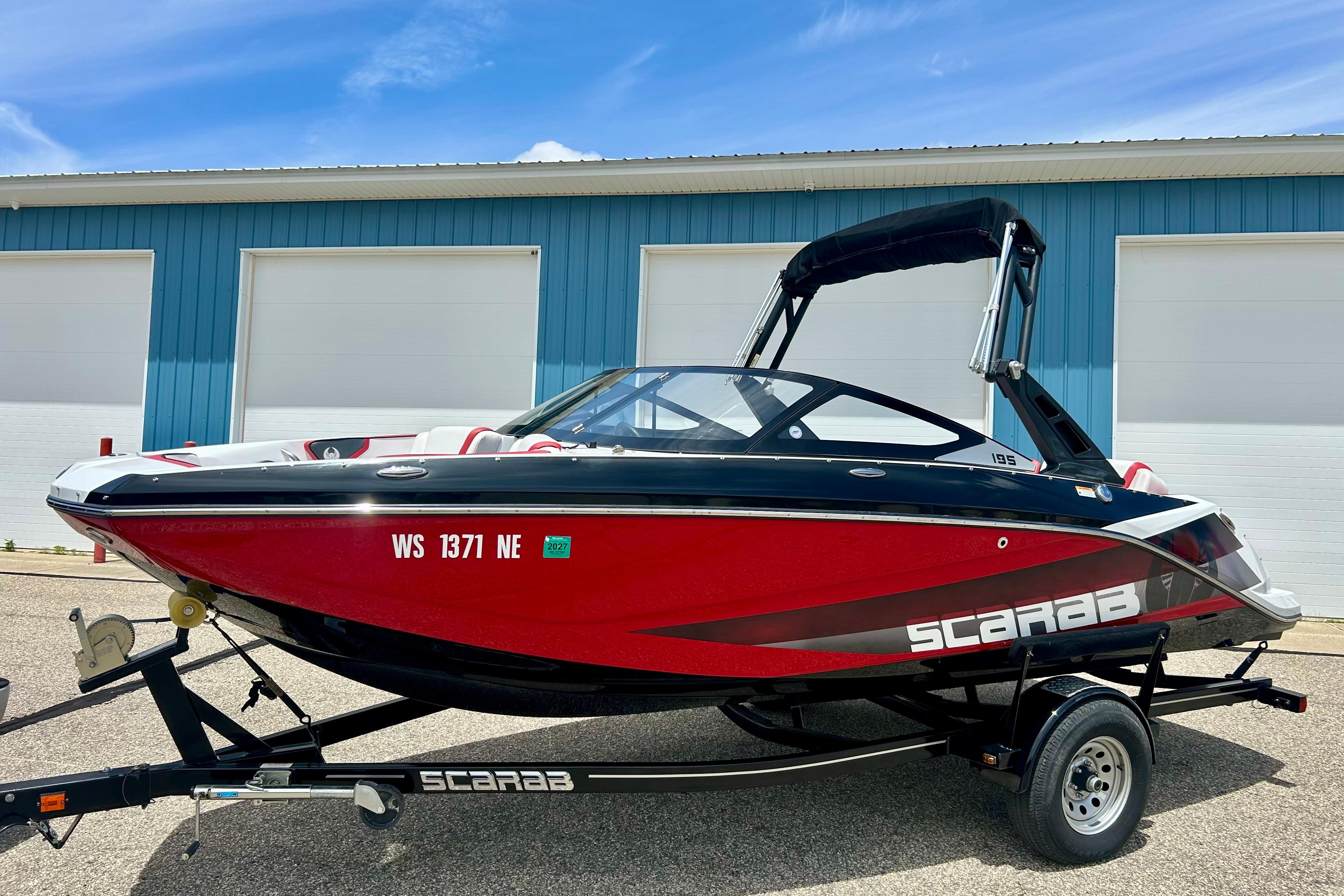 2021 Scarab 195 ID boat in red and black, parked on a trailer.