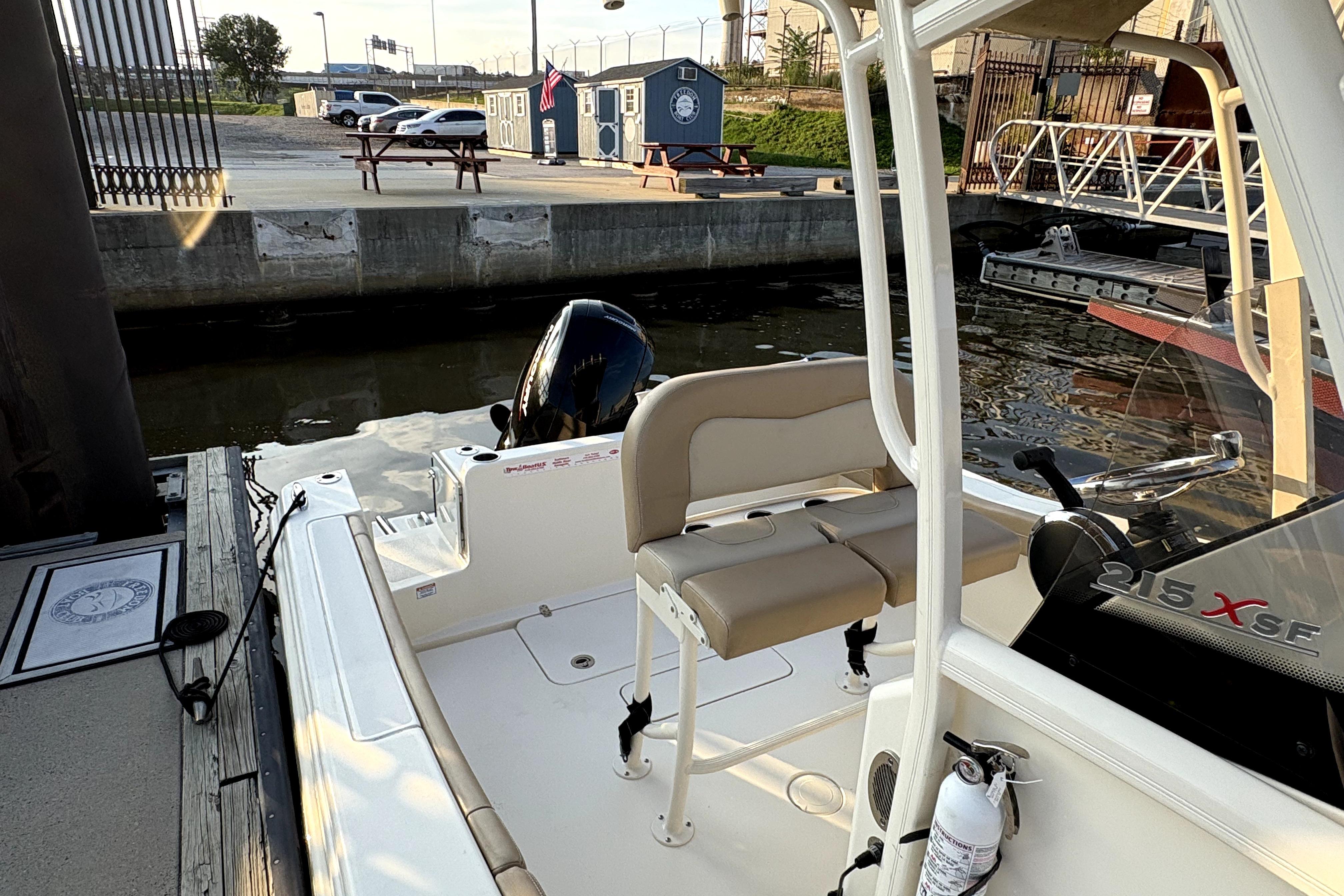 2023 Scout 215 XSF boat docked, featuring seating and outboard motor.