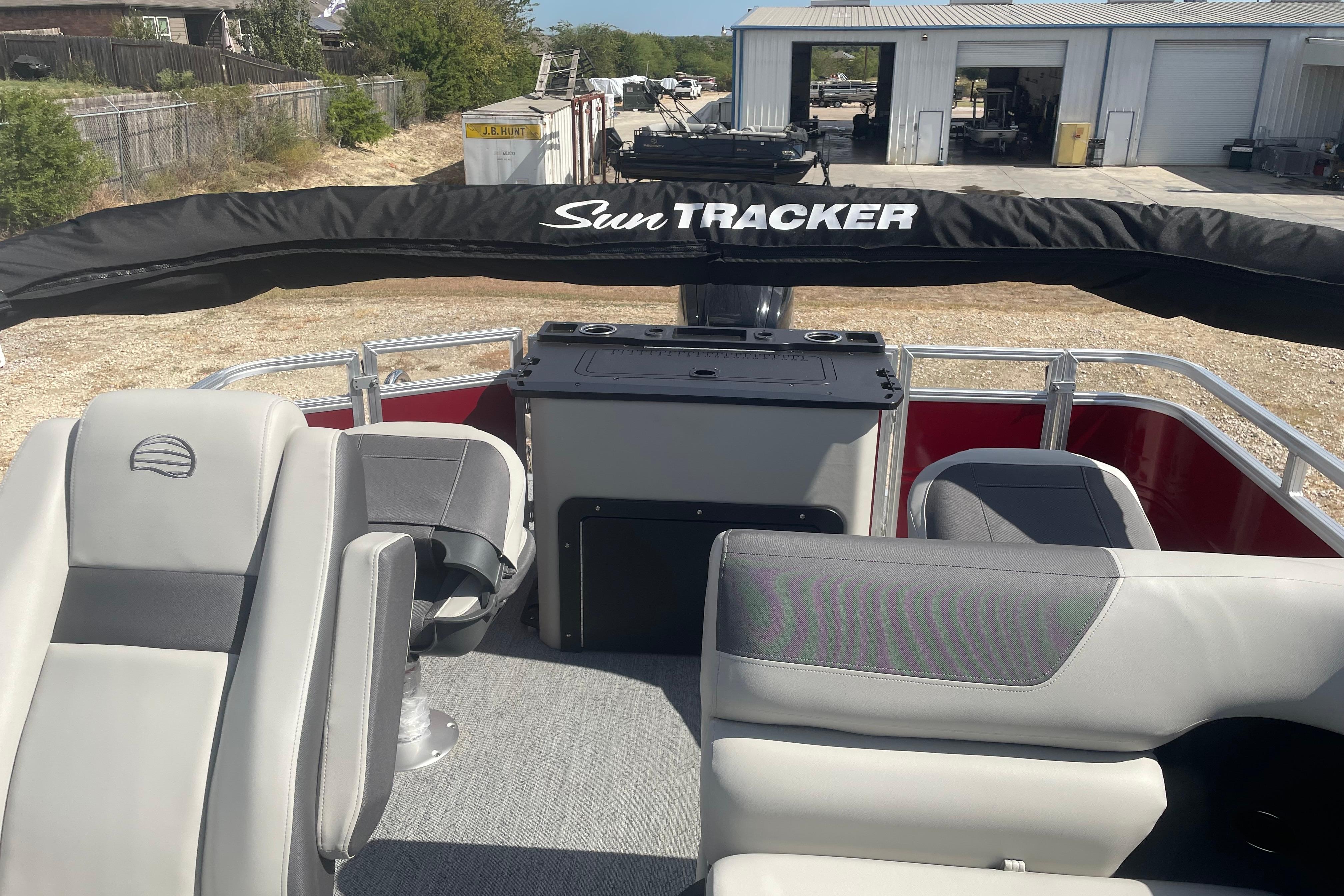 2026 Sun Tracker Fishin' Barge 22 DLX interior with seating and storage, parked outdoors.