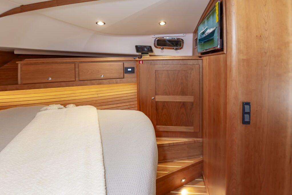 Interior of 2026 Sabre 43 Salon Express yacht with wooden cabinetry and cozy bedding.