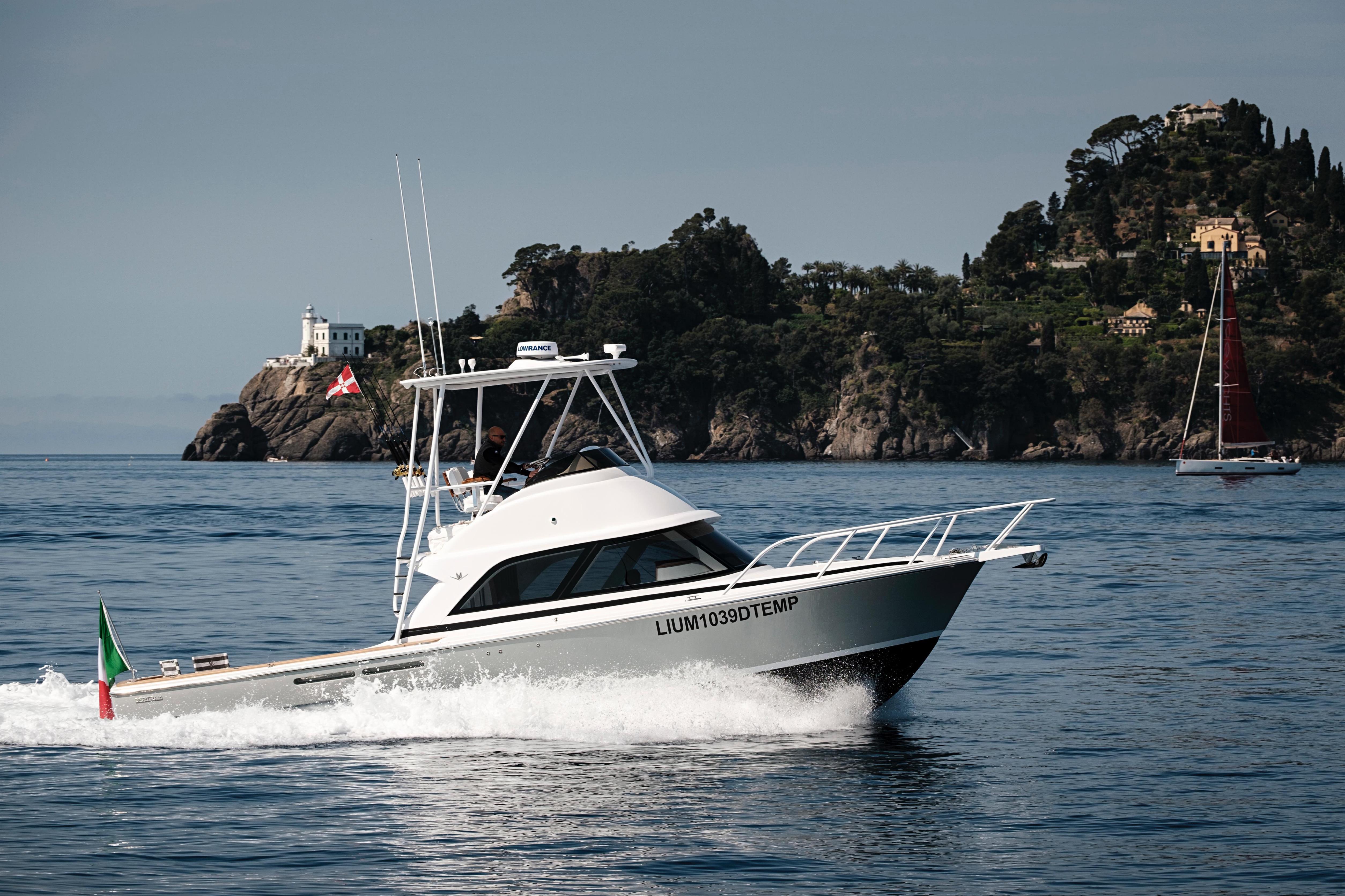 2023 Bertram Yacht 35 cruising near scenic coastline with lush greenery and distant sailboat.