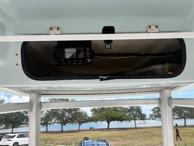 An open storage compartment on a boat with a view of a park and water.