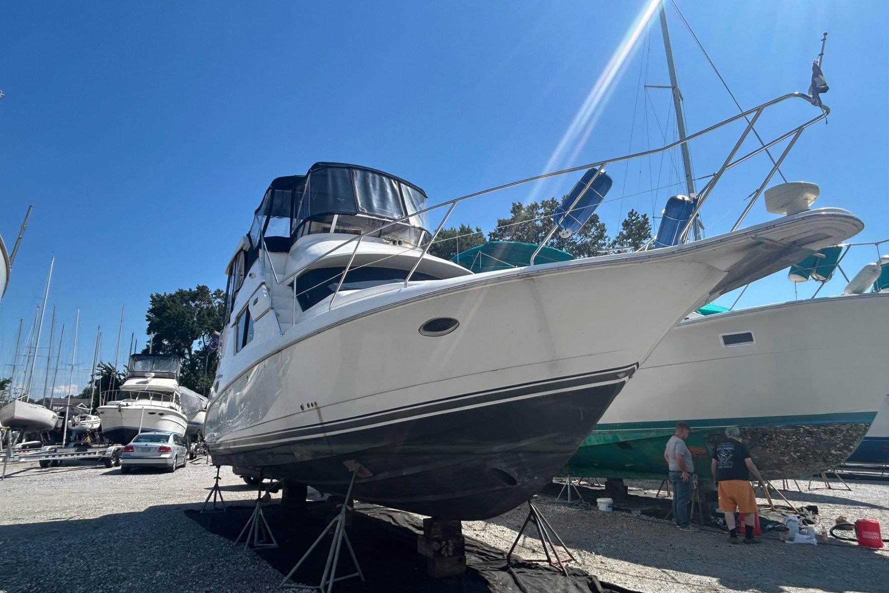 2000 Silverton 352 Motor Yacht on stands in a boatyard under clear blue sky.