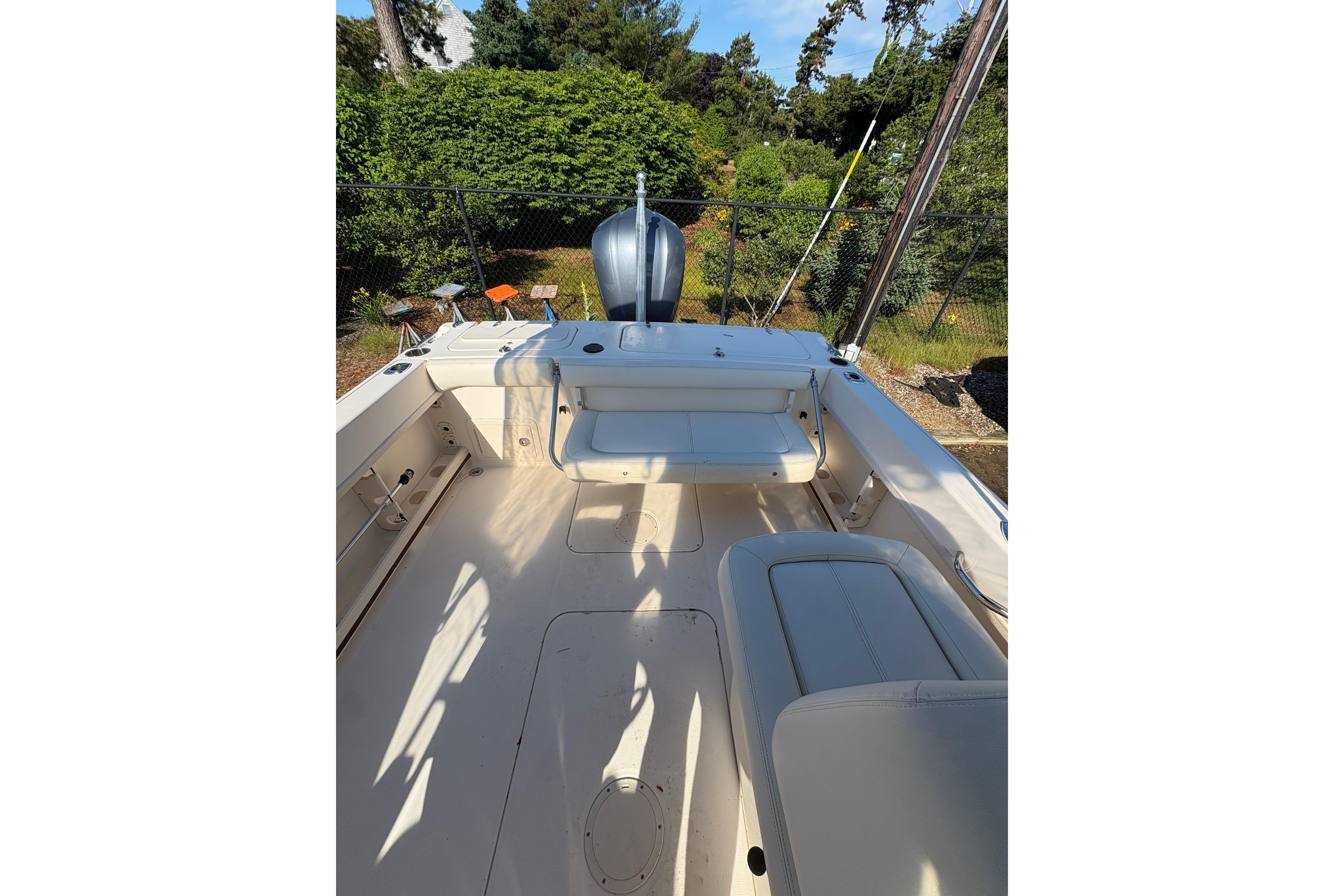 2015 Grady-White Freedom 225 boat interior with seating and motor, surrounded by greenery.